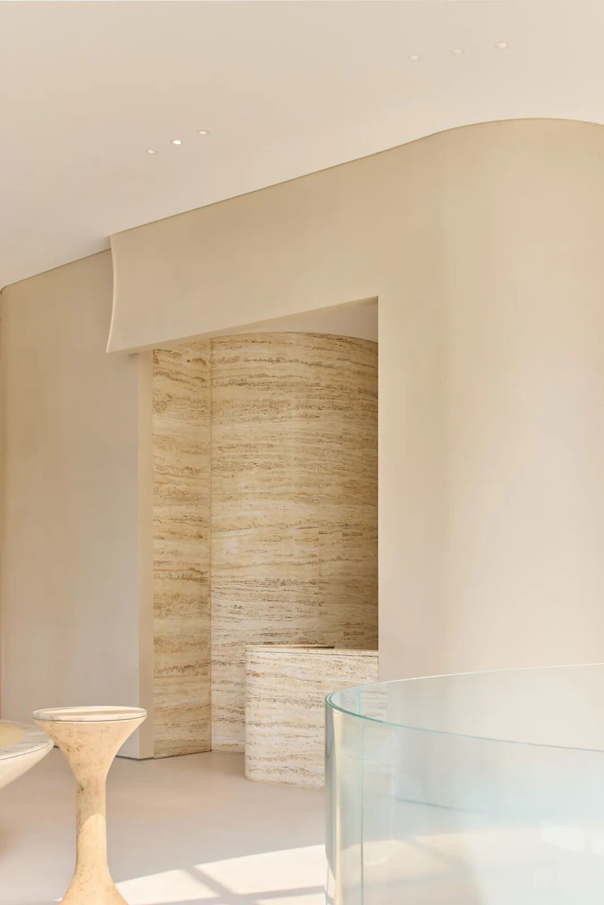 Bathroom with a shower on the left and a toilet on the right, featuring marble walls and a neutral color scheme