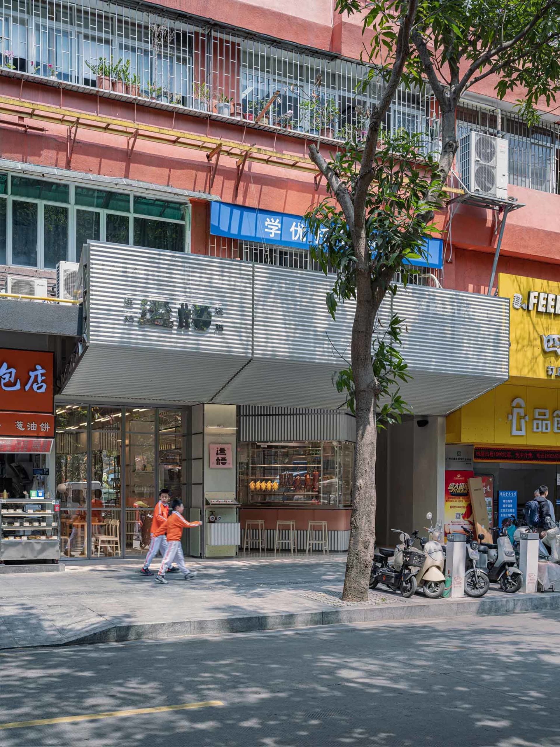 A street scene with a mix of modern and traditional buildings, lined with trees and featuring motorcycles, in warm earth tones with natural sunlight