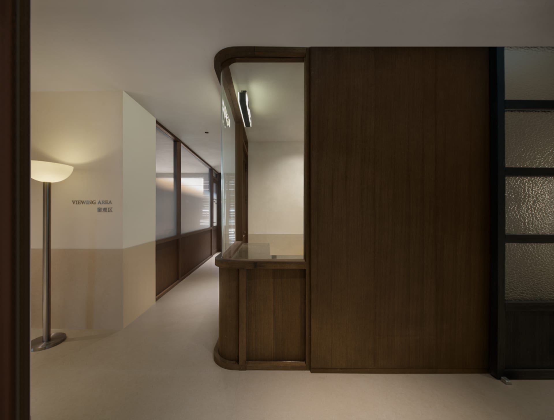 Dimly lit hallway with a wooden wall and counter, featuring a simple and functional design