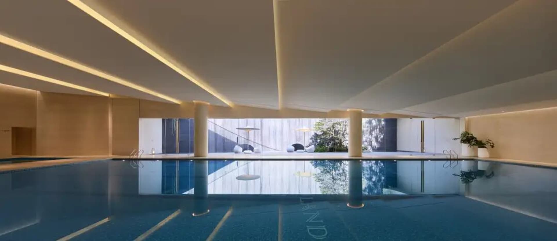 A relaxing pool area with a hotel building in the background, surrounded by a deck and chairs, inviting guests to unwind