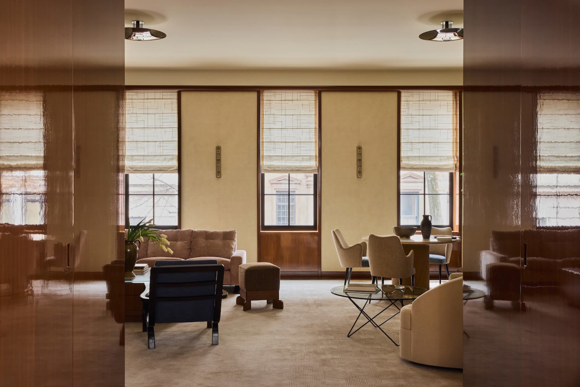 A modern living room with a couch, chair, dining table, and potted plant, featuring soft and warm lighting, creating a cozy and inviting atmosphere