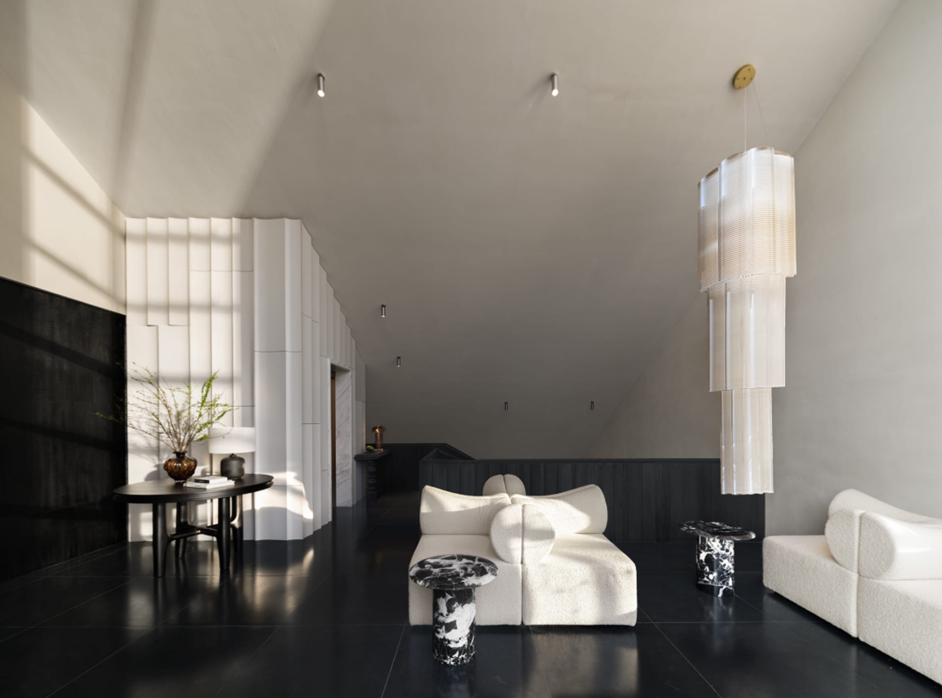 A well-lit living room with a black floor, a white couch, a chair, and two potted plants, giving a modern and stylish look