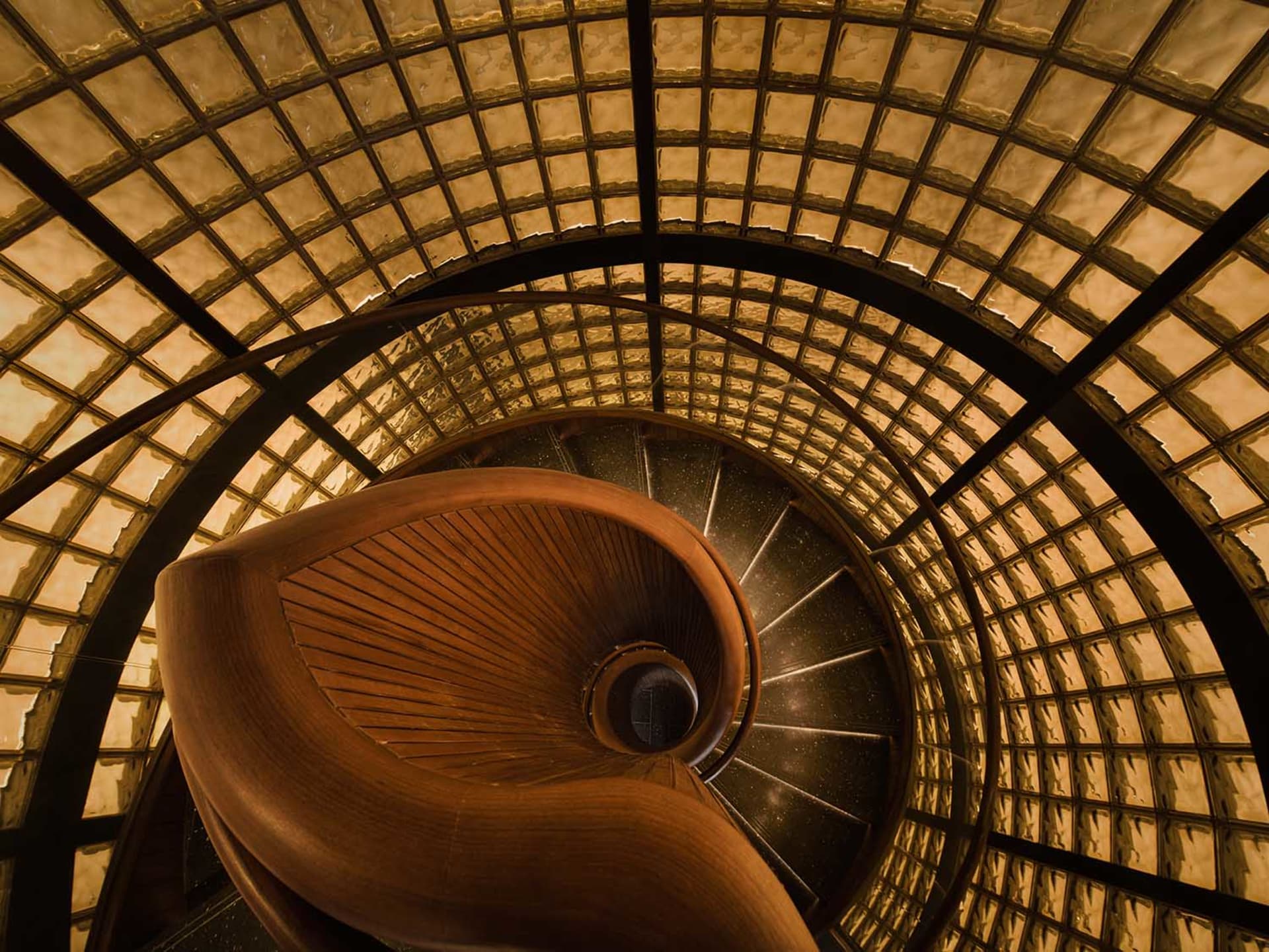 A dimly lit spiral staircase with intricate wooden treads and a sense of history and craftsmanship