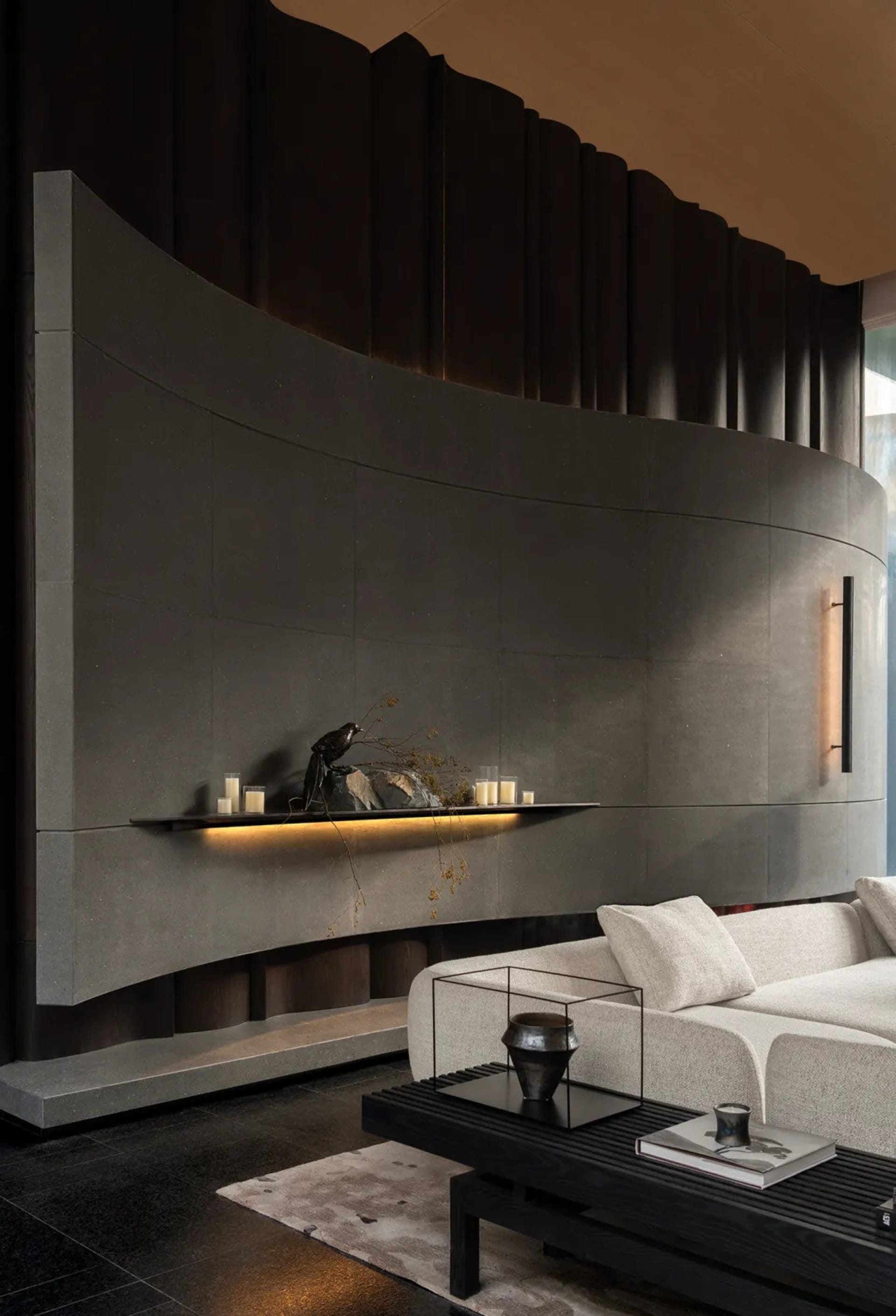 Cozy living room with a modern design, a large couch, a fireplace, and a black bird statue, set against a black and white color scheme