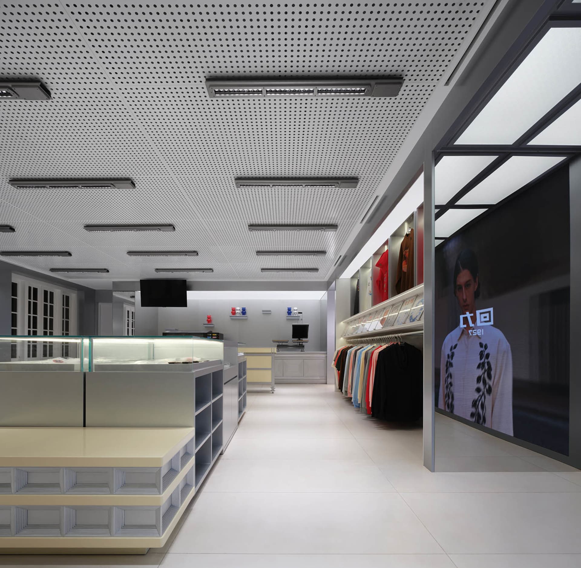 A modern retail store with a large open floor plan, featuring clothing items on racks and a display window, under bright and well-distributed lighting