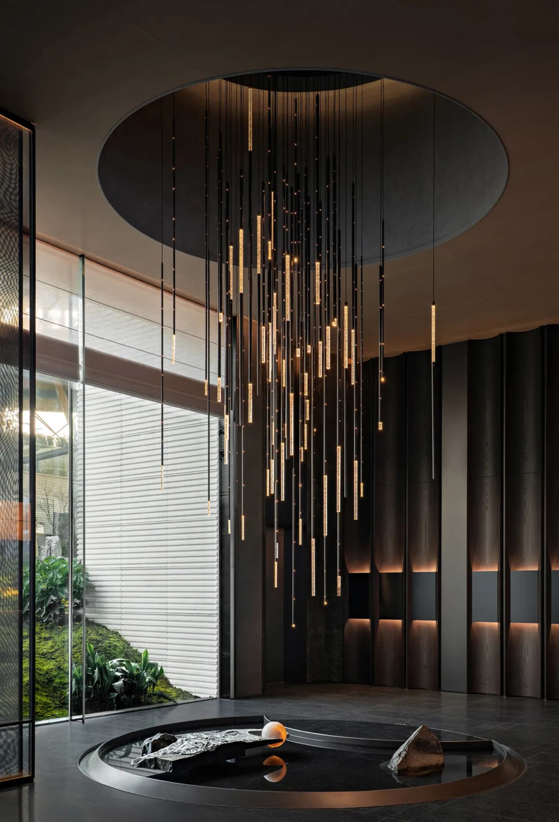 Modern dining room with a metal chandelier, large window, and potted plants, featuring clean lines and minimalistic design