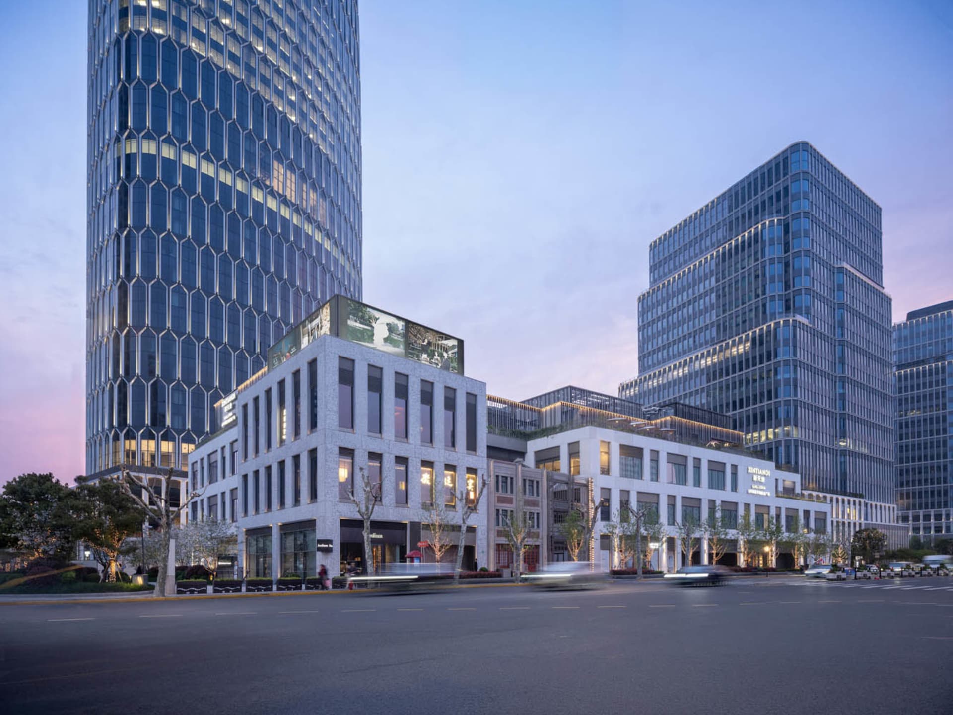 夜晚的城市街道，旁邊是一棟大型玻璃建築，街燈照亮四周，充滿都市生活氣息