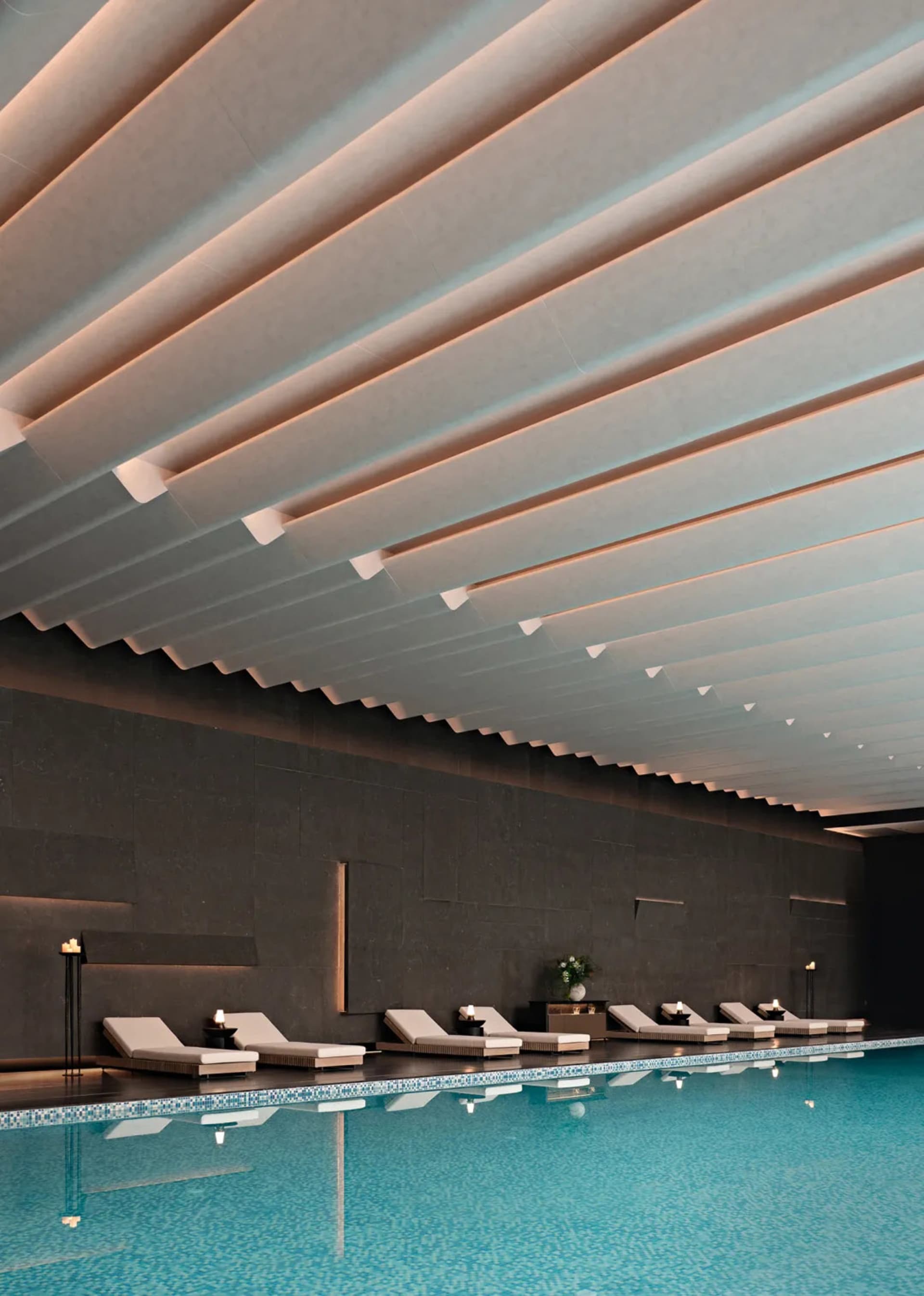 A spacious pool area with lounge chairs and a large white ceiling, surrounded by a luxurious and relaxing environment