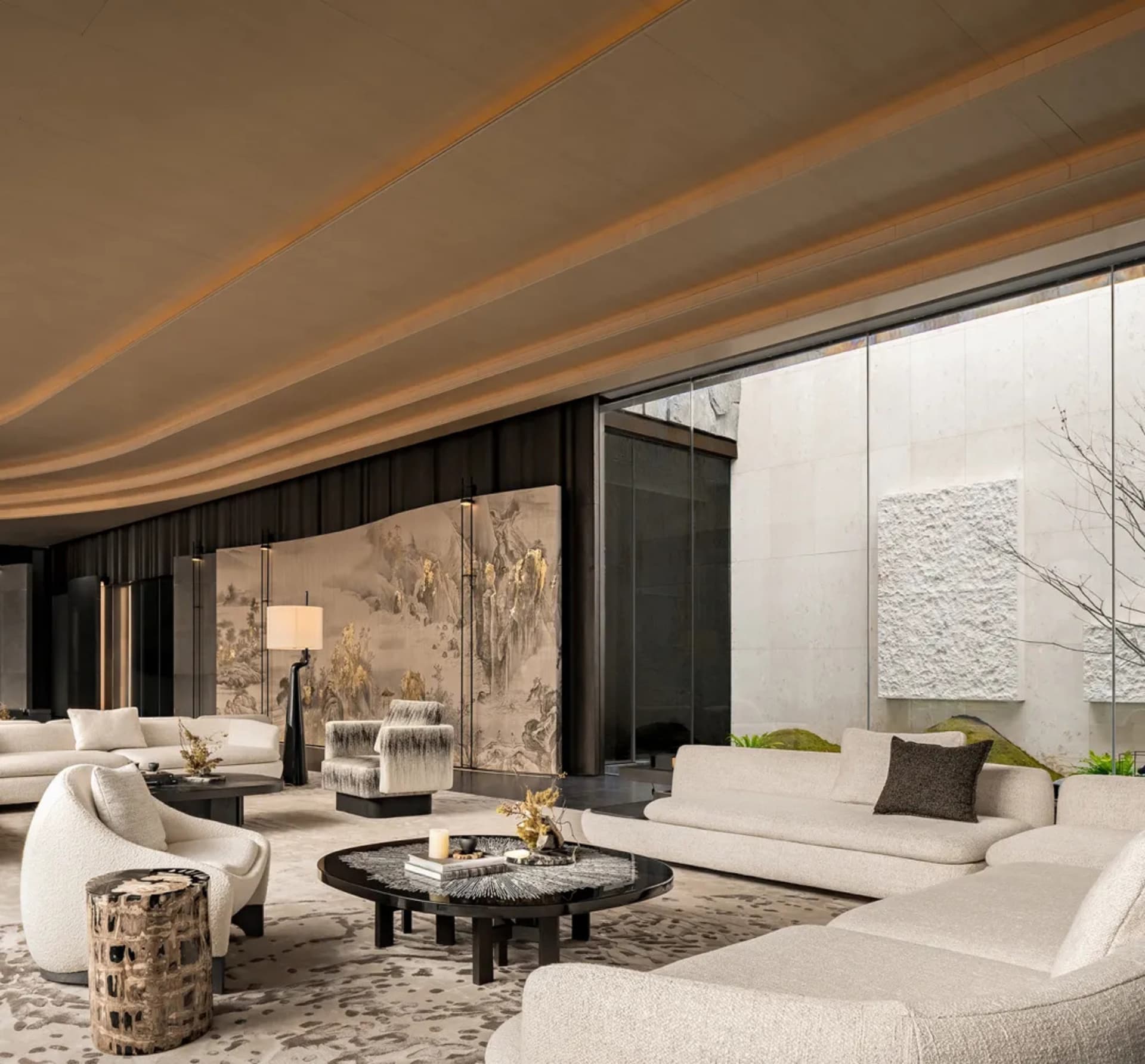 Cozy living space with a large couch, chair, coffee table, and decorative elements, featuring soft warm lighting and natural light from windows