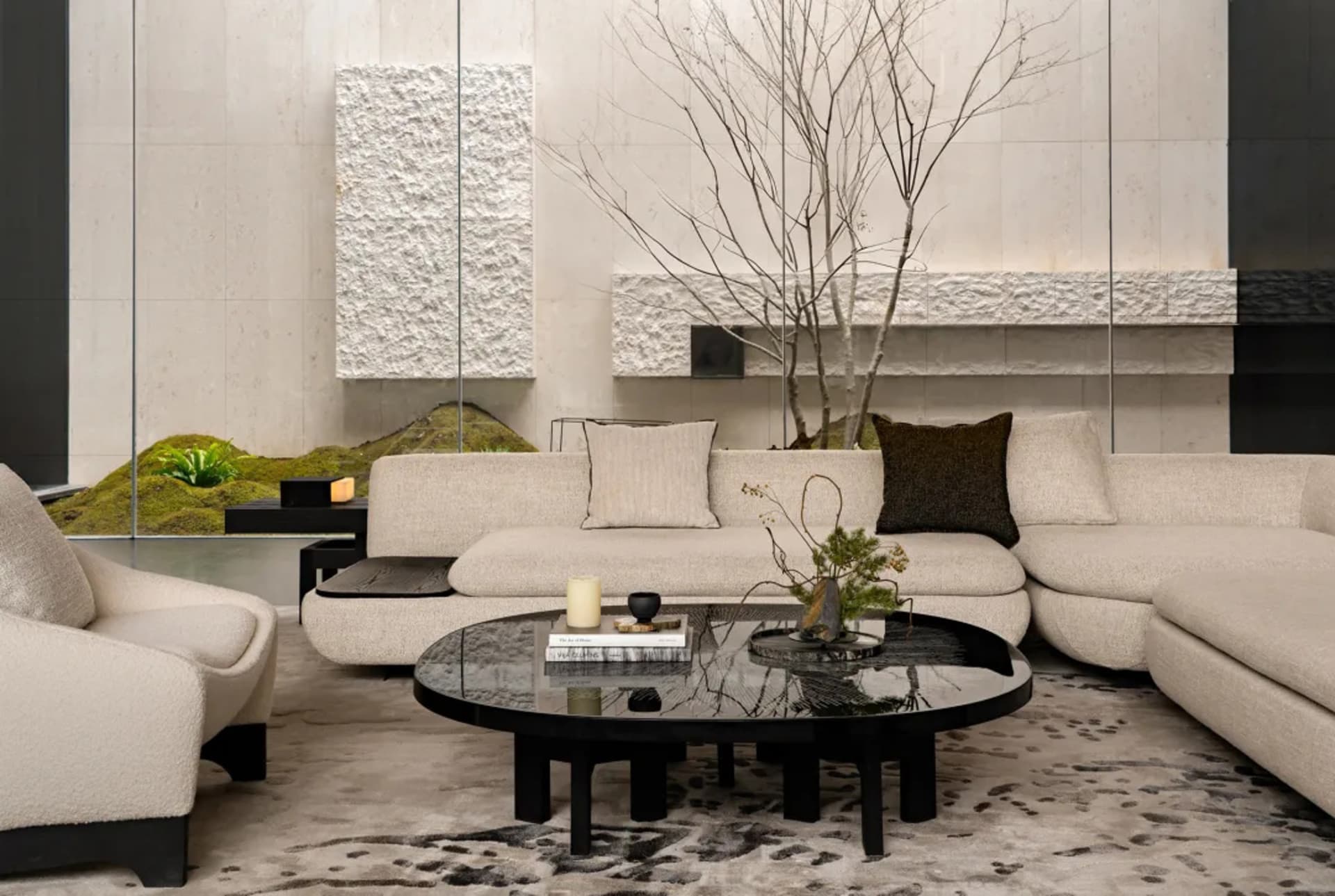 A modern living room with a black coffee table, couch, and chair, decorated with potted plants and featuring clean lines and minimalistic decor