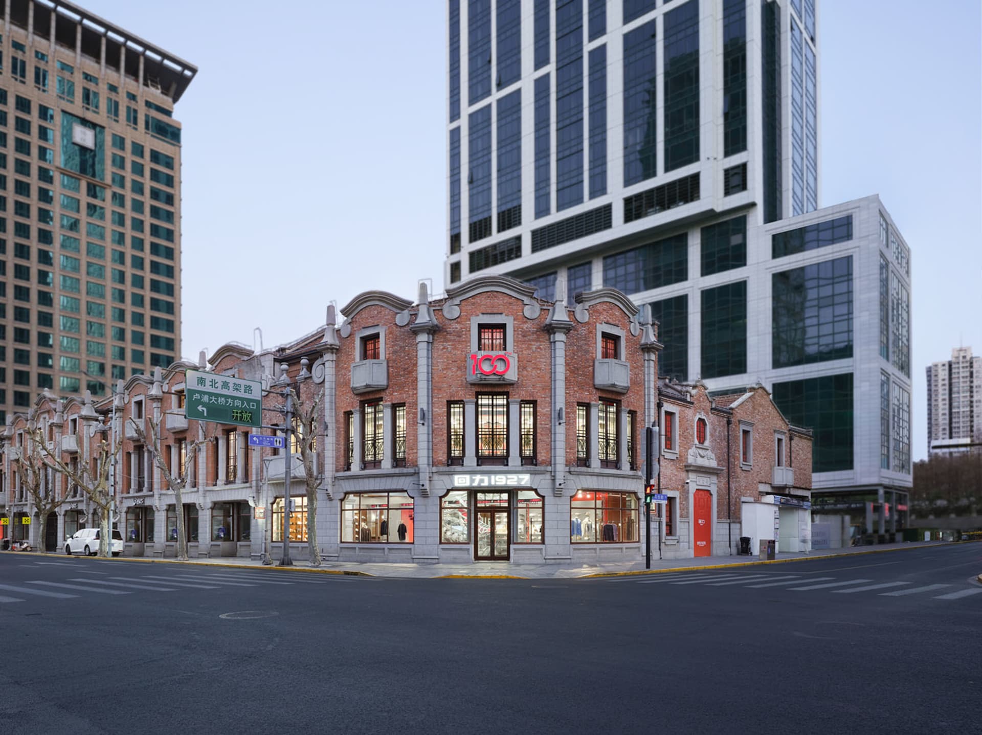 A large ornate building with a prominent red brick facade, clock tower, and arched entrance, set in a city environment with soft and diffused lighting