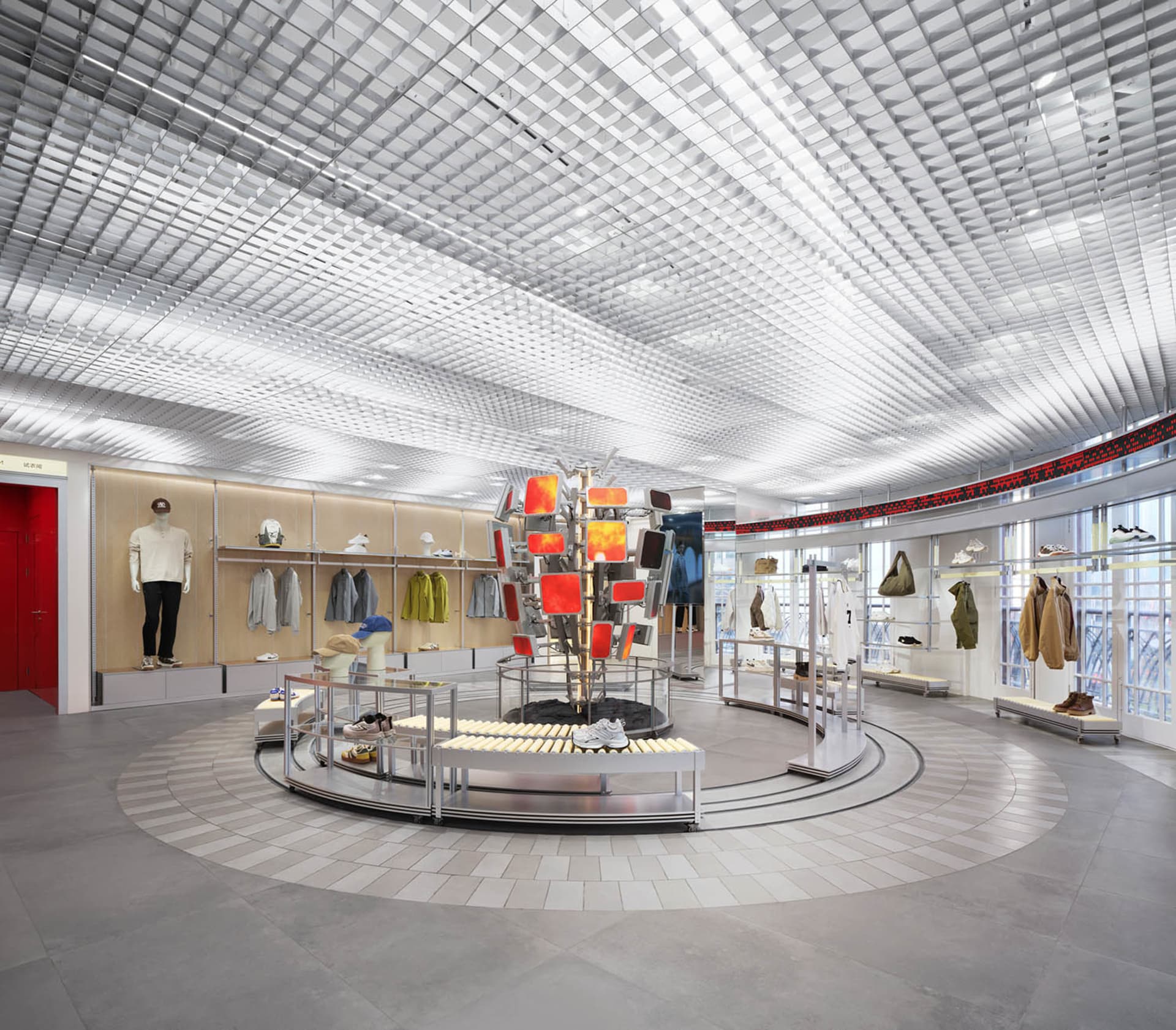 A modern retail store with a circular display in the center, surrounded by clothing items and bright lighting, creating a welcoming atmosphere