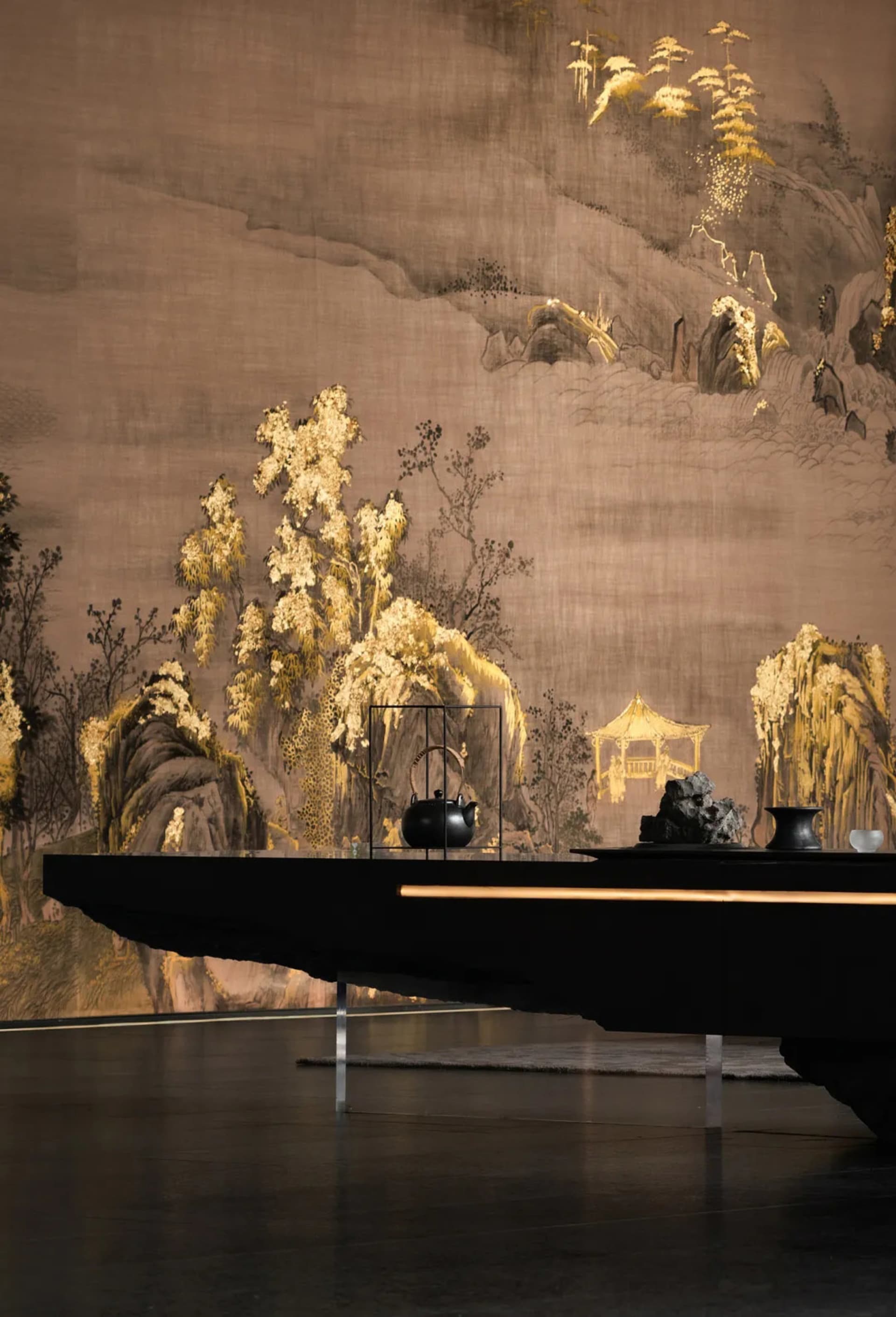 A luxurious dining space with a black table, gold wall, and a large painting, surrounded by vases and exuding an elegant atmosphere