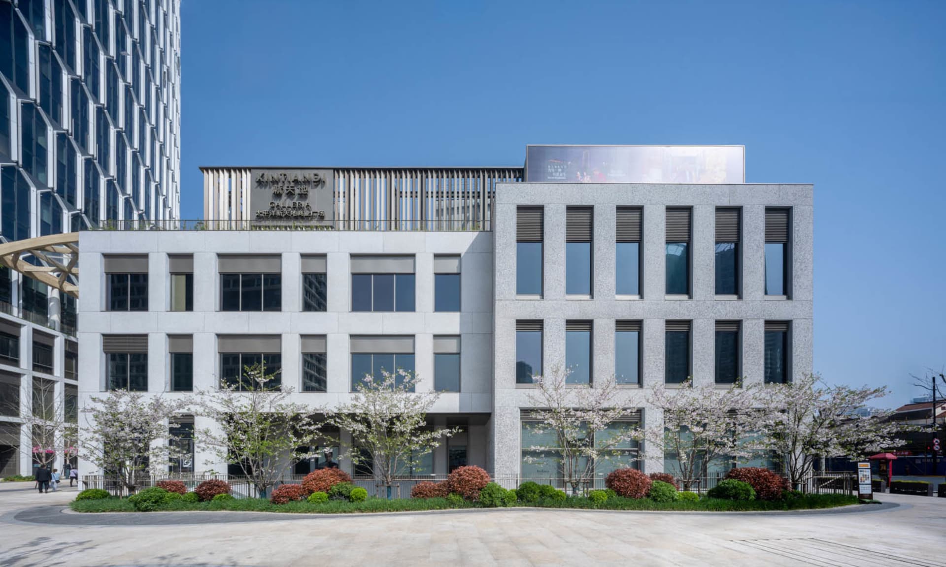 A modern office building with a concrete exterior and glass windows, bathed in natural sunlight, creating a bright and inviting atmosphere