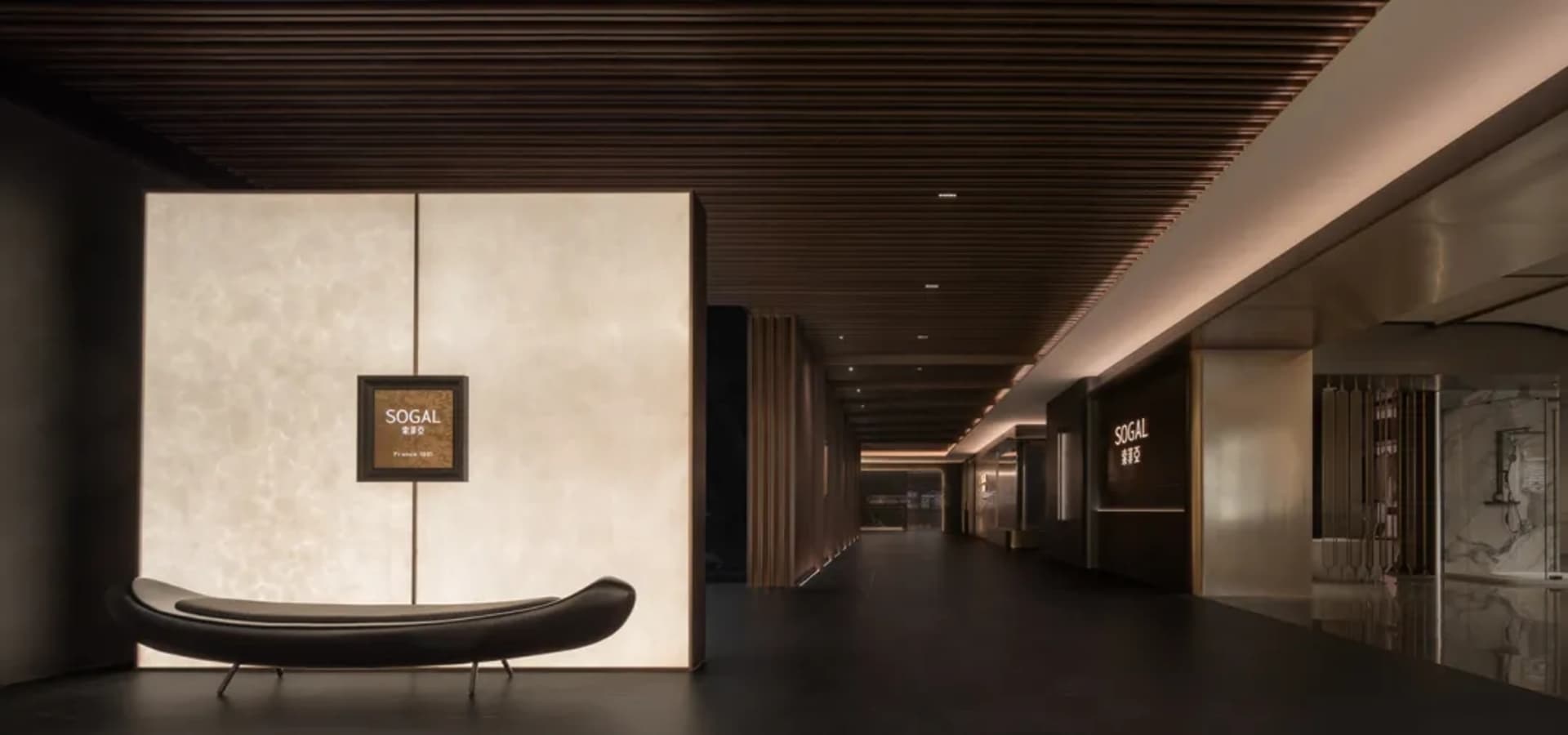 A modern lobby with a wooden floor, white walls, and a couch, featuring a bench in the center of the room