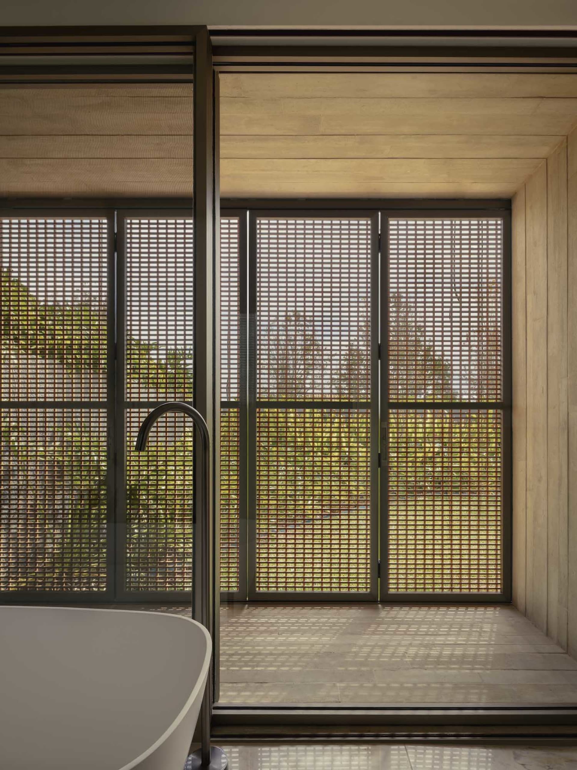 Bathroom with a bathtub and shower, surrounded by concrete walls and natural light from windows