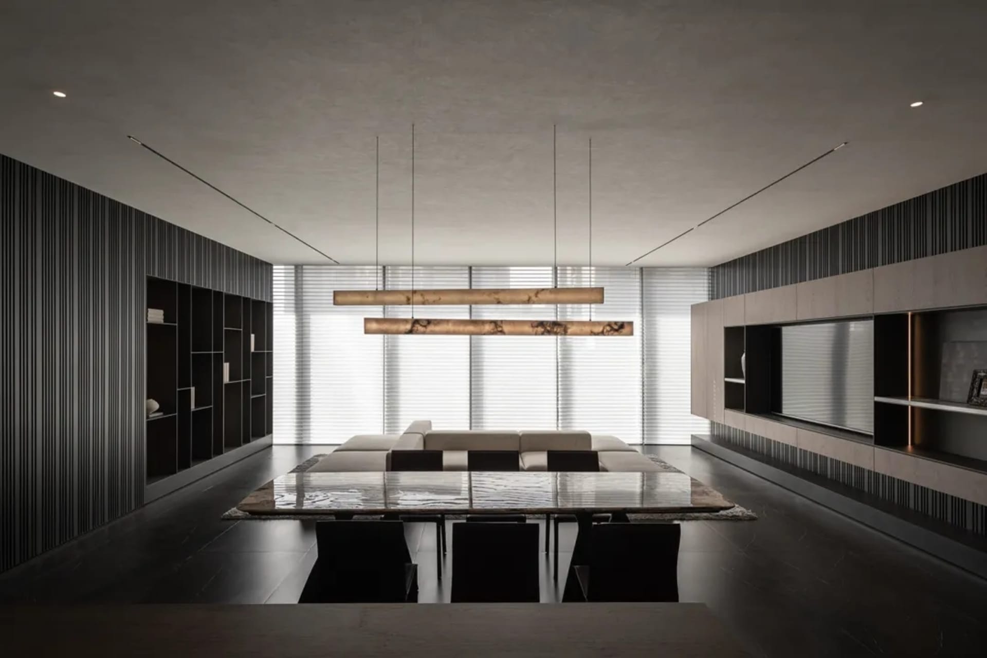 A spacious living room with a long dining table and chairs, a couch, and a hanging light fixture, in a contemporary style