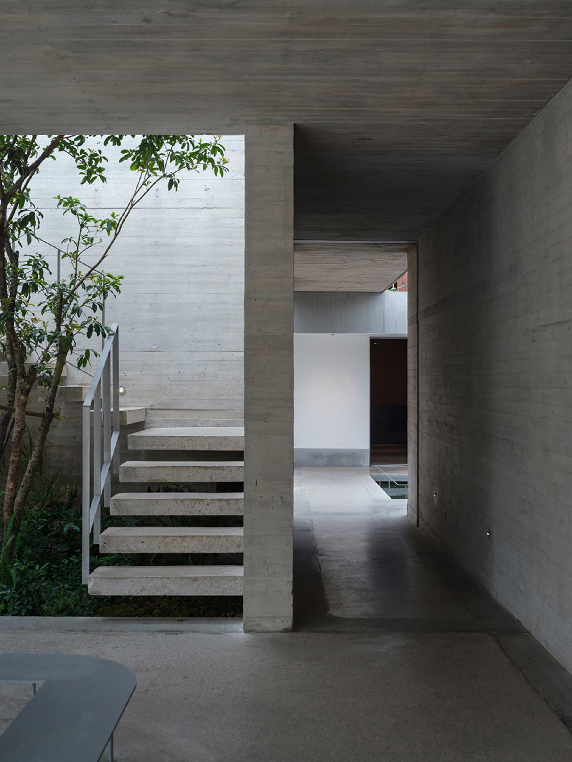 Modern building with concrete and metal materials, natural light, and a staircase leading to a doorway