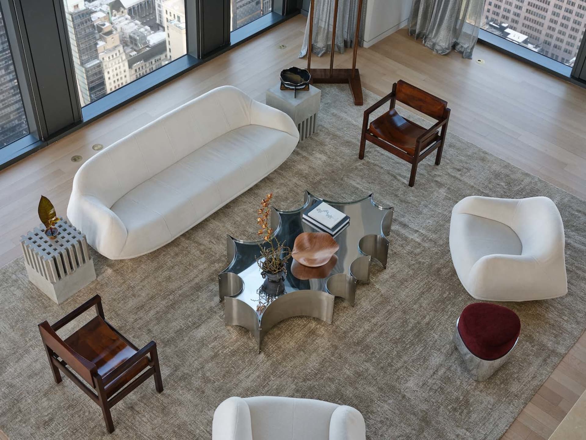 A modern living room with a white couch, a chair, and a coffee table, decorated with a rug and surrounded by various pieces of furniture and books, in a well-lit and inviting atmosphere
