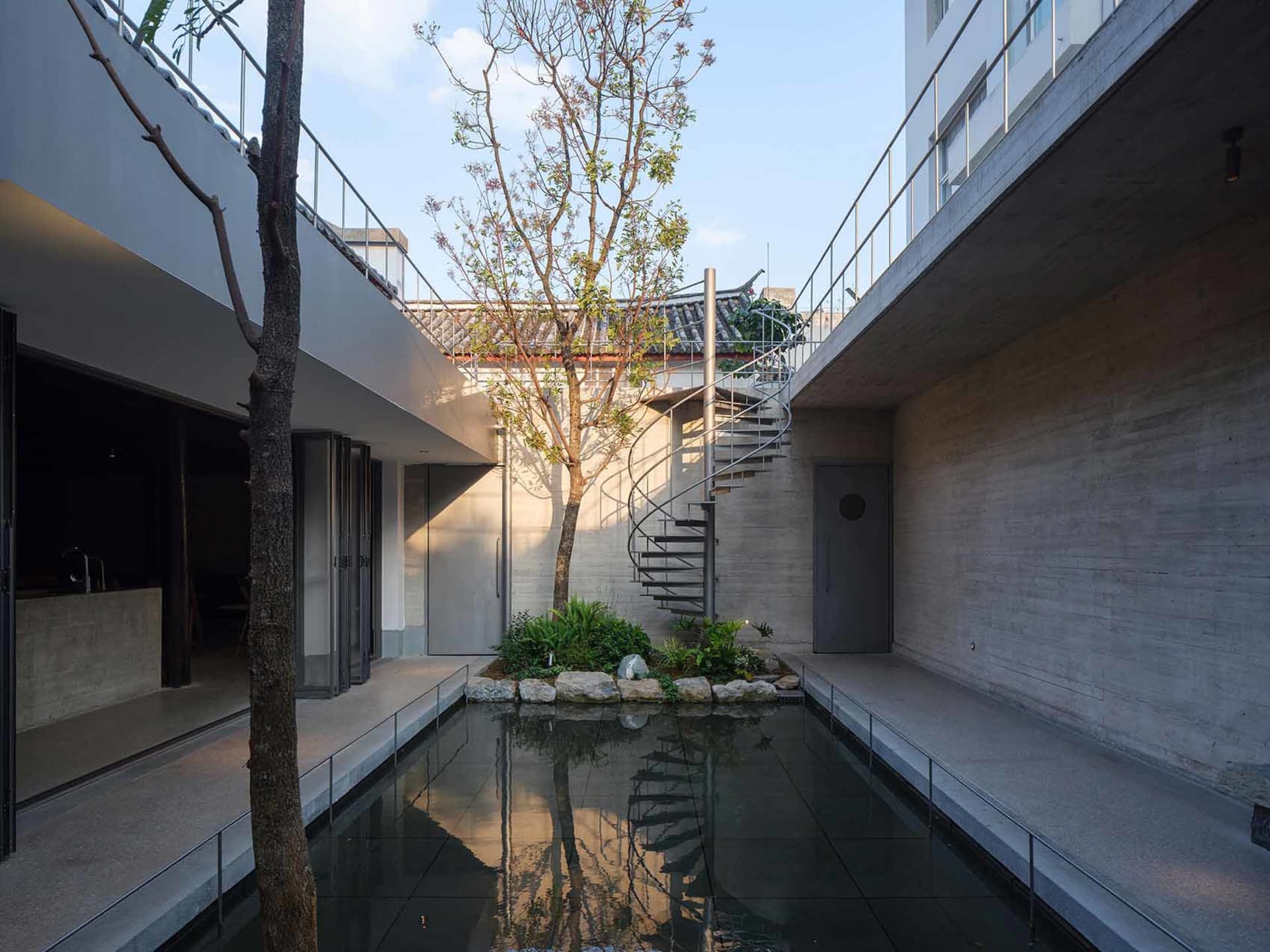 現代建築場景，呈現大型開放空間，搭配混凝土樓梯與水池，周圍有自然光線與大窗