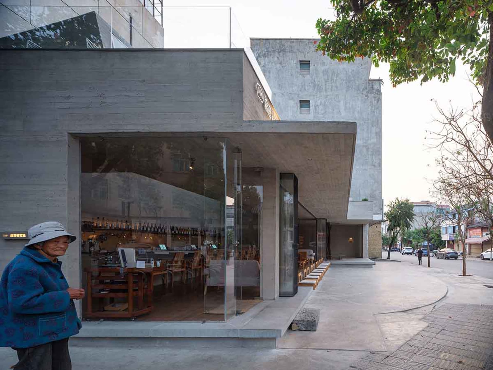Modern restaurant interior with a large glass wall, wooden tables, and chairs, flooded with natural light