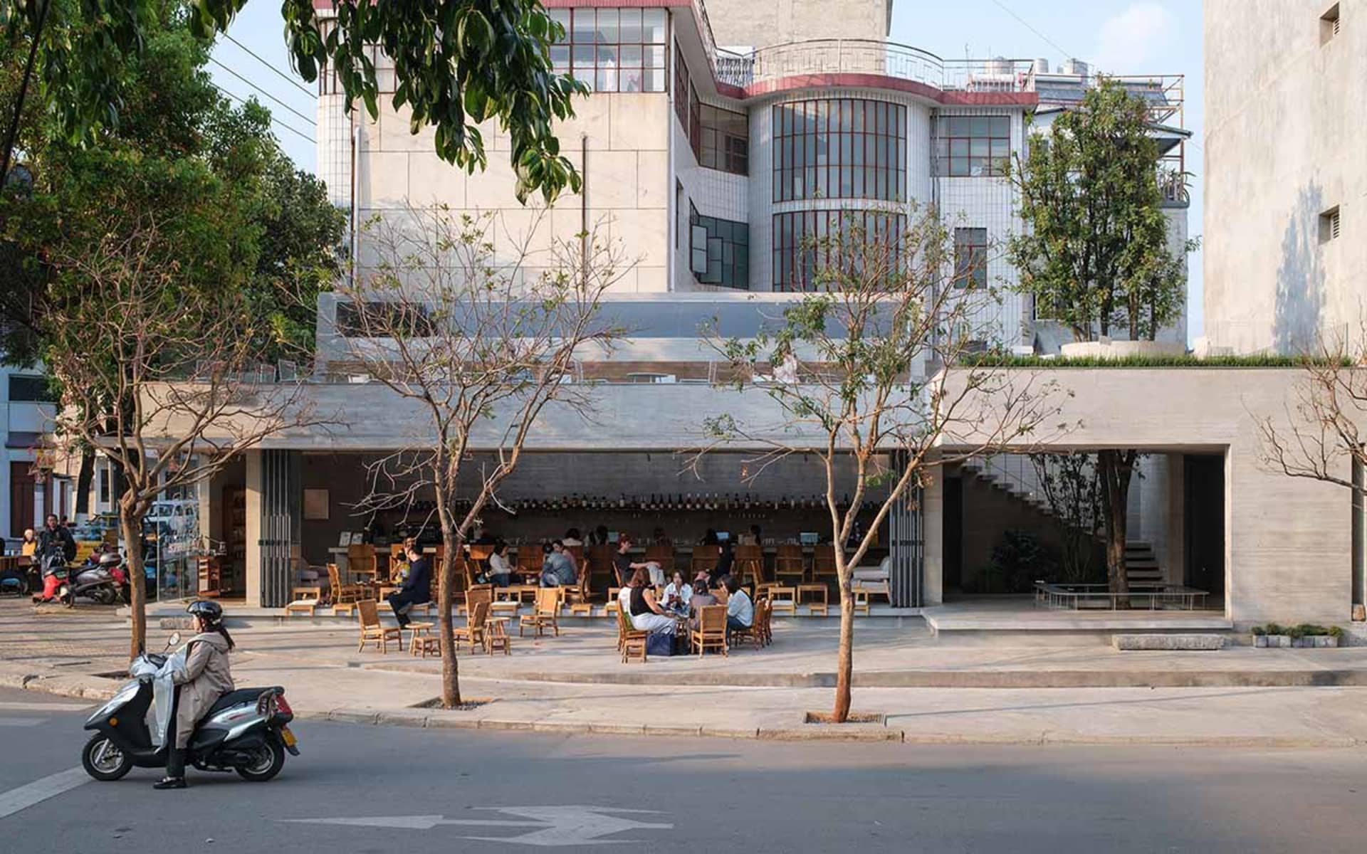 現代設計的戶外餐廳，運用木質與混凝土元素，周圍有賓客坐在桌邊，營造休閒放鬆的氛圍