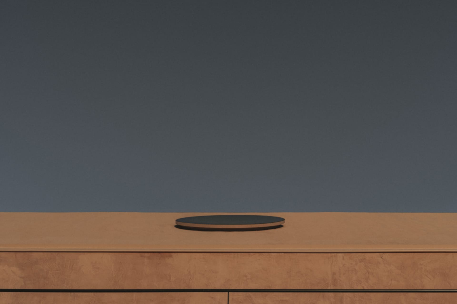 A room with a wooden table and a circular object on top, set against a grayish-brown background