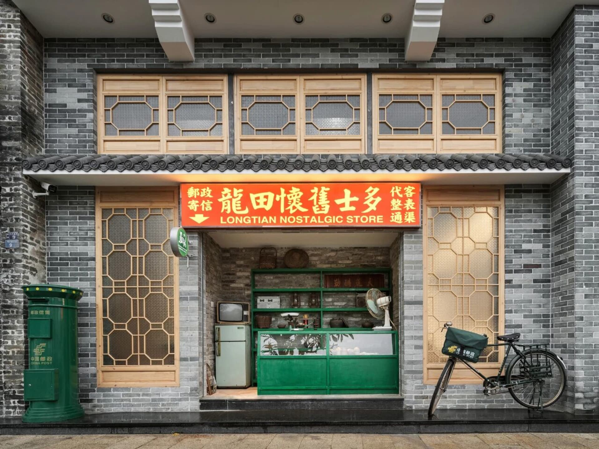 A vintage storefront with a green door and Chinese sign, featuring a window display with a bicycle and a glimpse into the world of antiques and nostalgic items