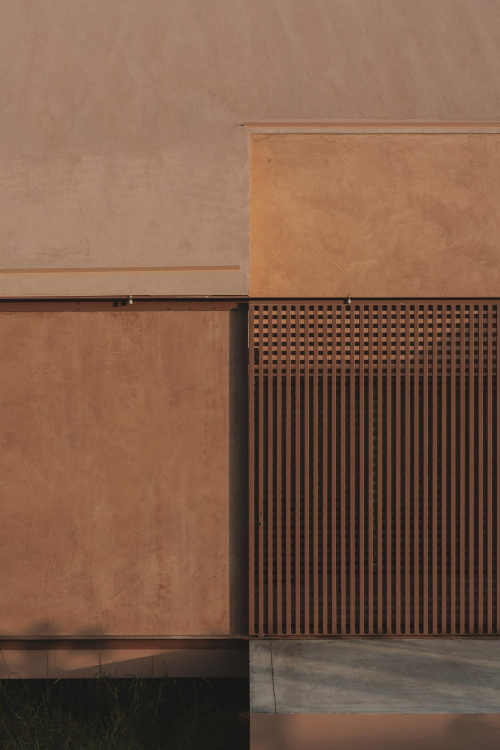 A modern building with a brown brick wall and a white wall, set against a natural background with warm and inviting lighting