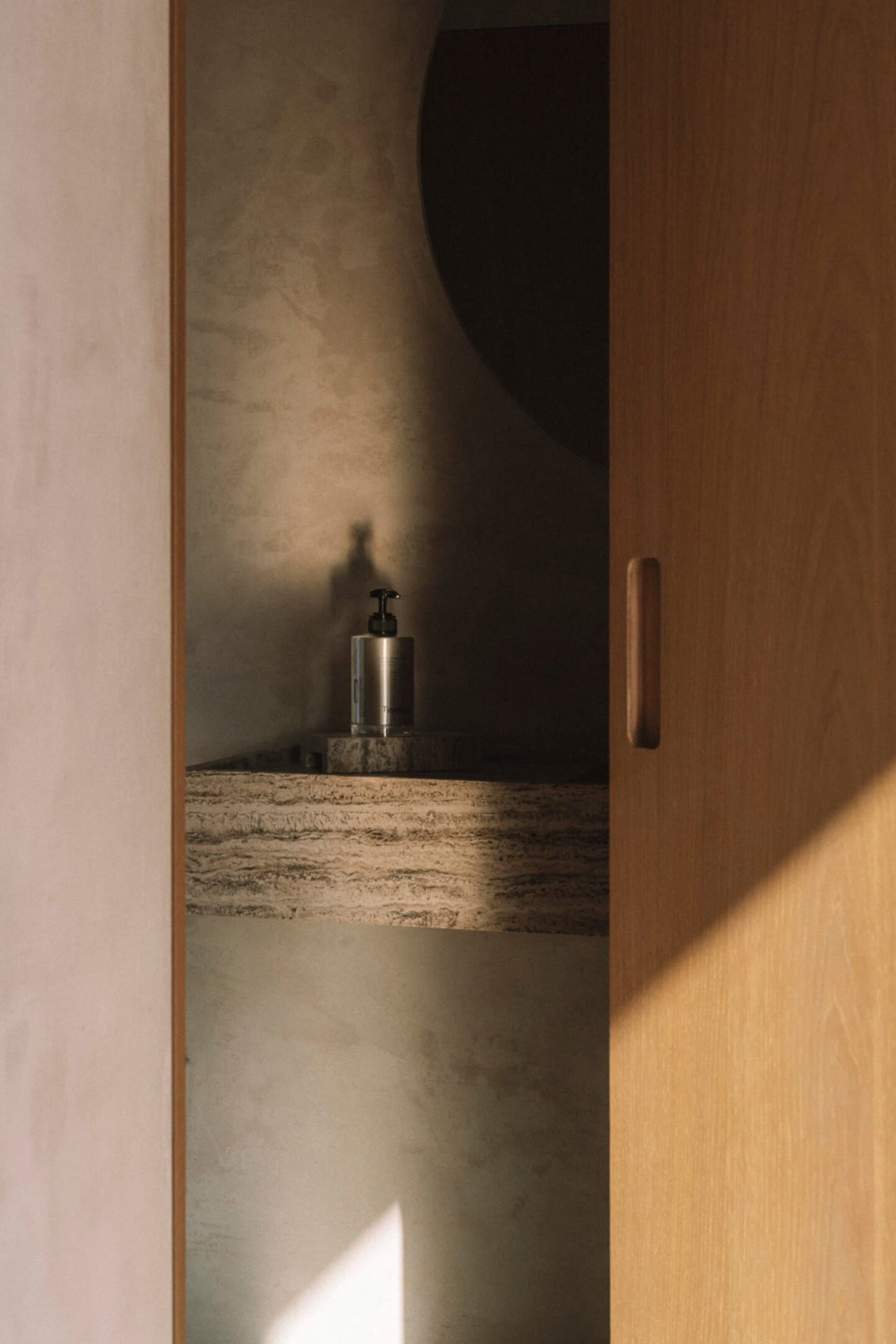Bathroom with a sink and a bottle on the counter, surrounded by wooden surfaces and dim lighting