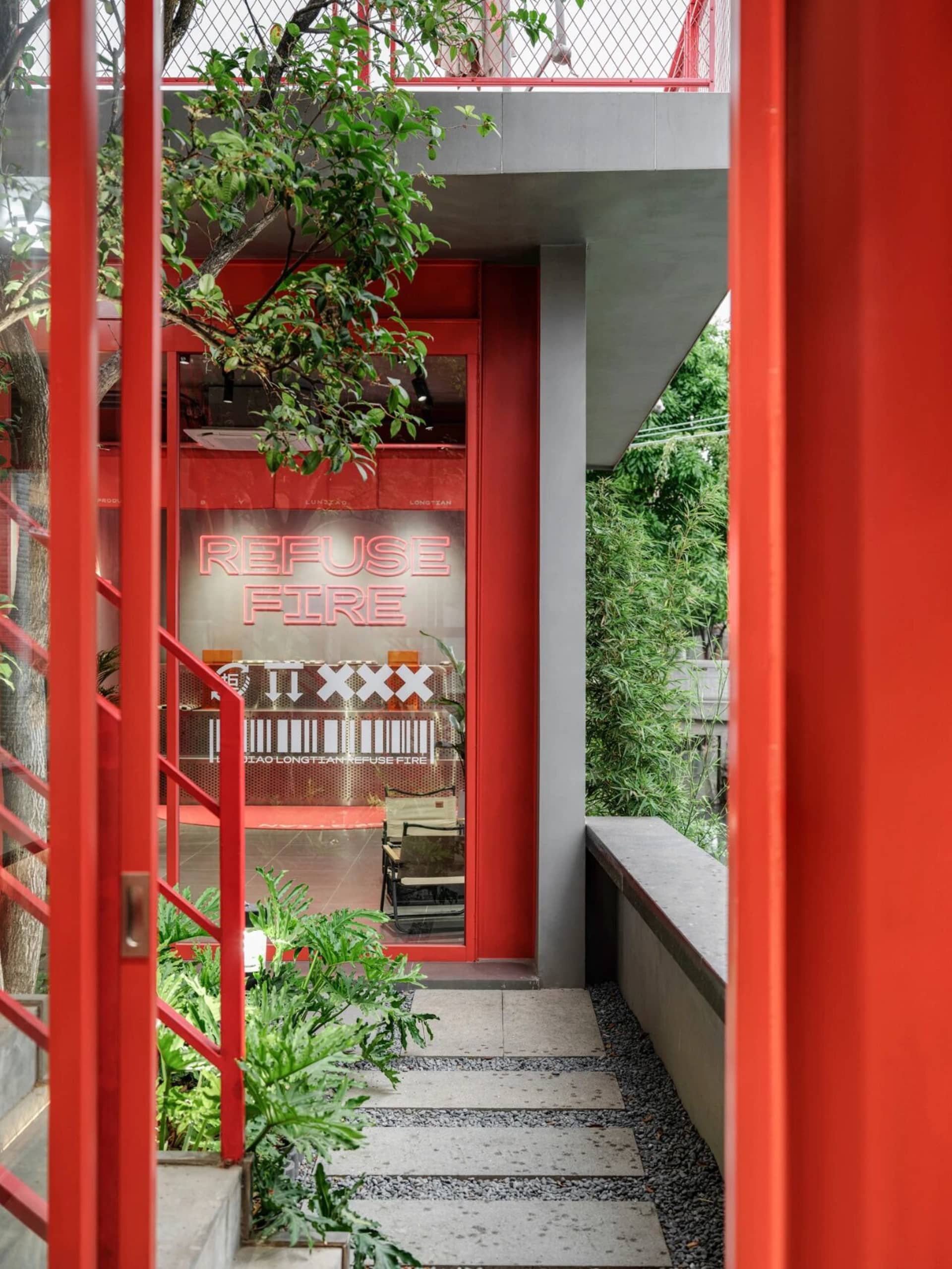 Photograph of a red building with a metal staircase, concrete walls, and natural light from windows