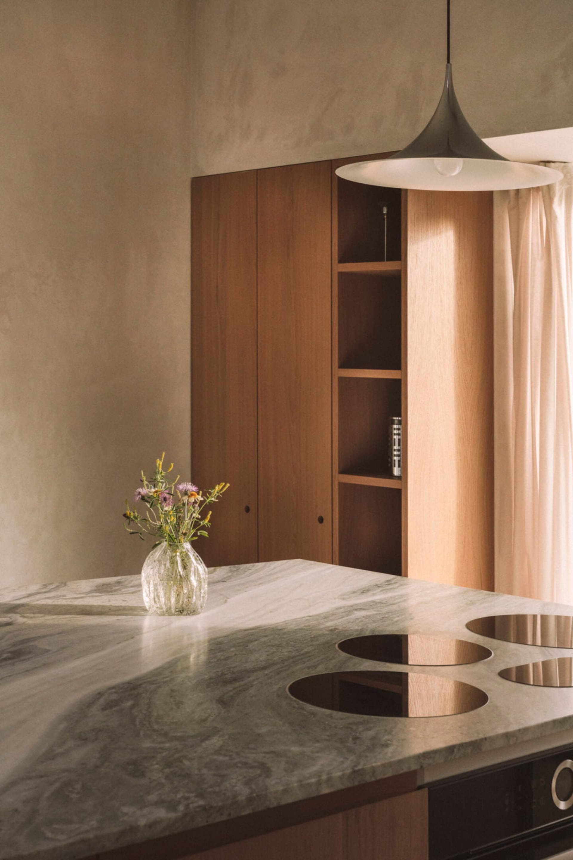 A well-lit kitchen dining area with a marble table, wooden cabinet, and potted plant, creating a warm and inviting atmosphere