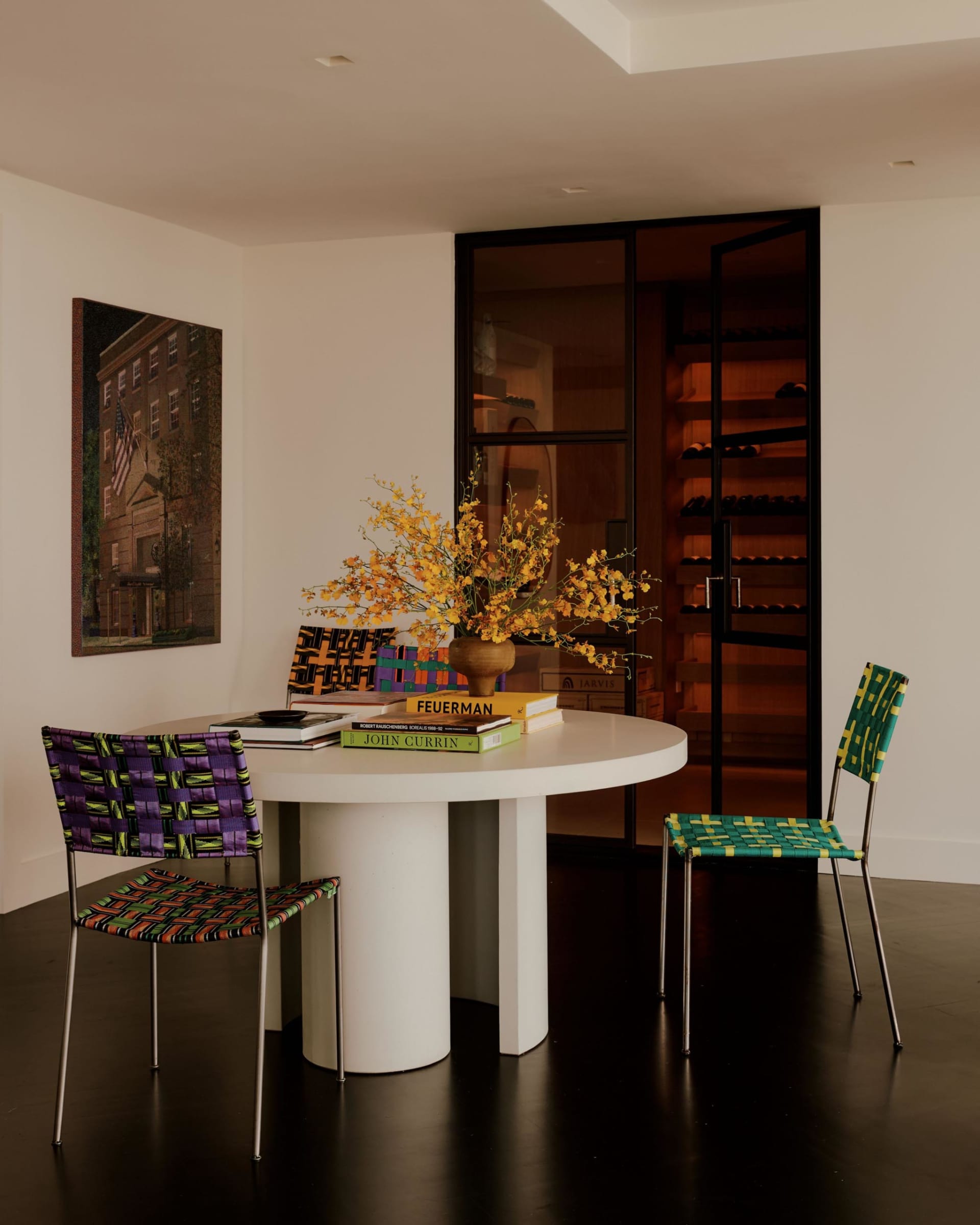 A well-lit living room with a white table, chairs, a vase with flowers, a dining table, and a potted plant, featuring a combination of wood and glass materials