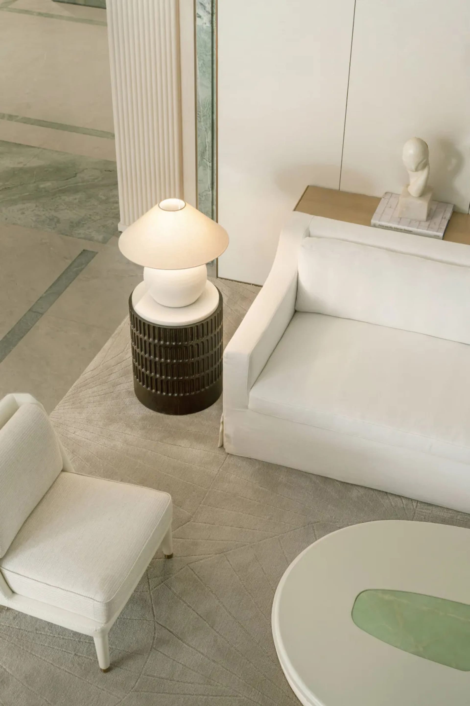 A minimalist living room with a white couch, chair, and coffee table, well-lit and decorated with simplicity and white color