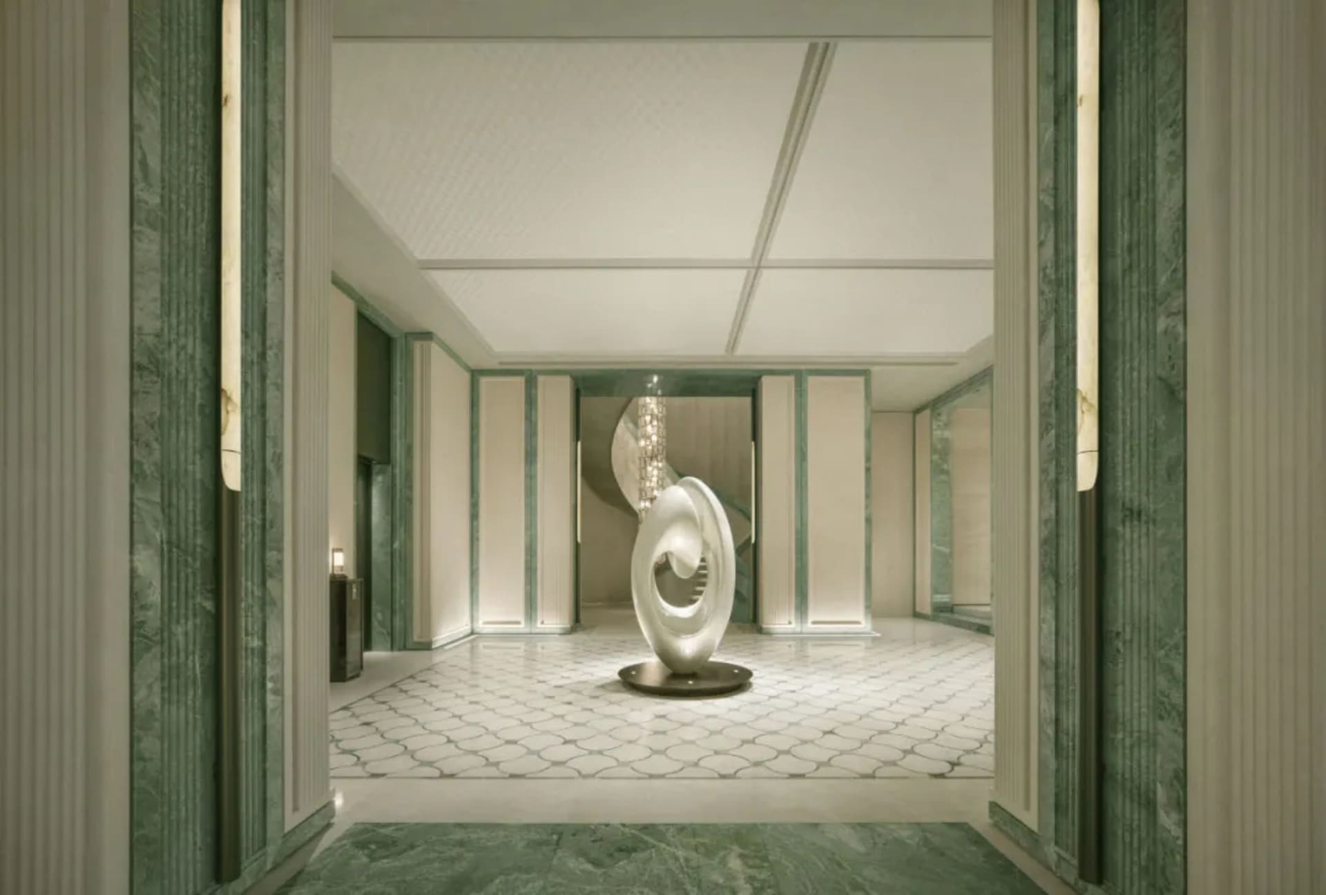 A well-lit, modern room with a white color scheme, a circular sculpture, chandelier, and decorative vase, creating an elegant and sophisticated atmosphere