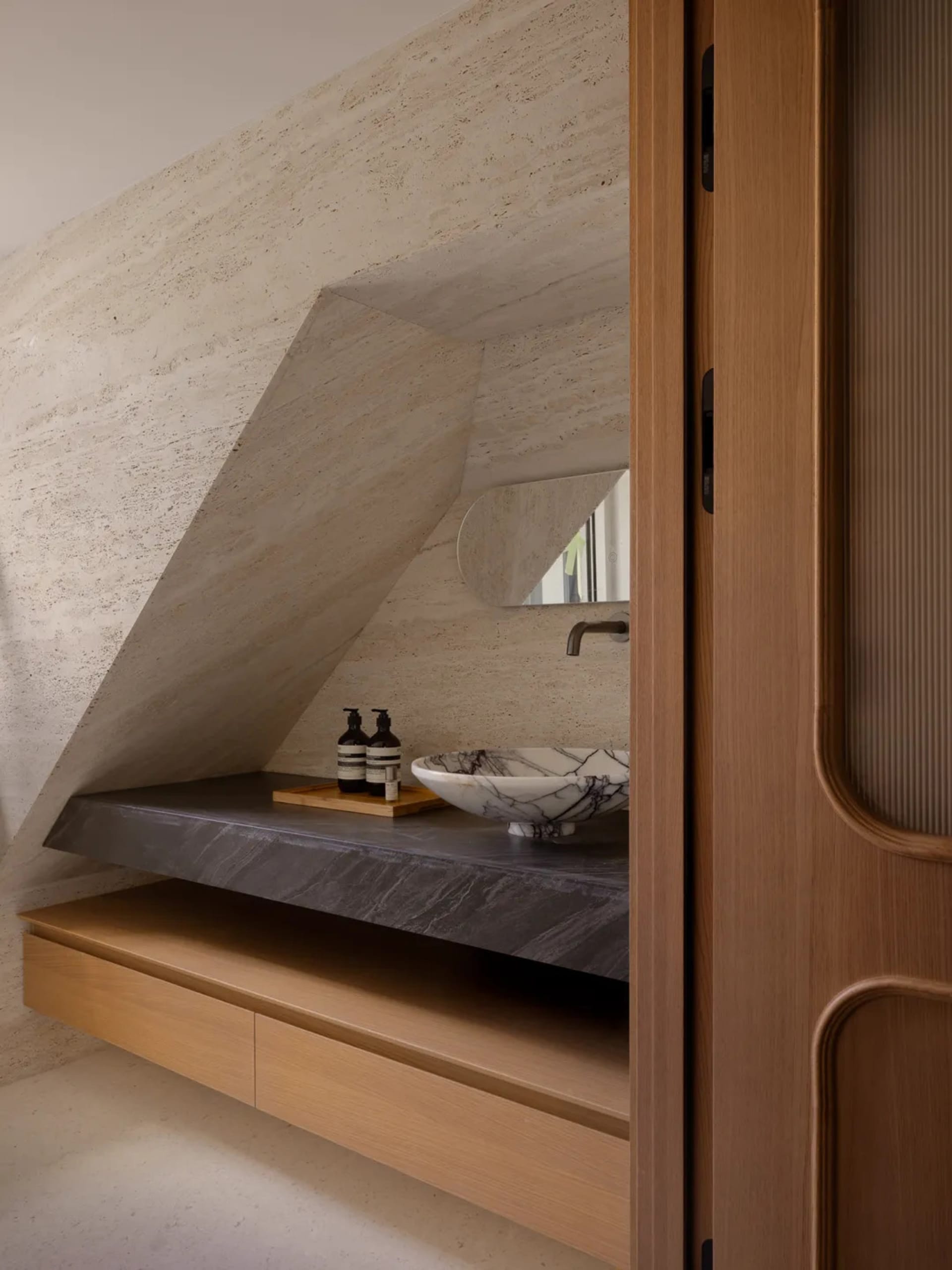Modern bathroom with a slanted ceiling, a wooden cabinet, and a sink, featuring a practical and clean design