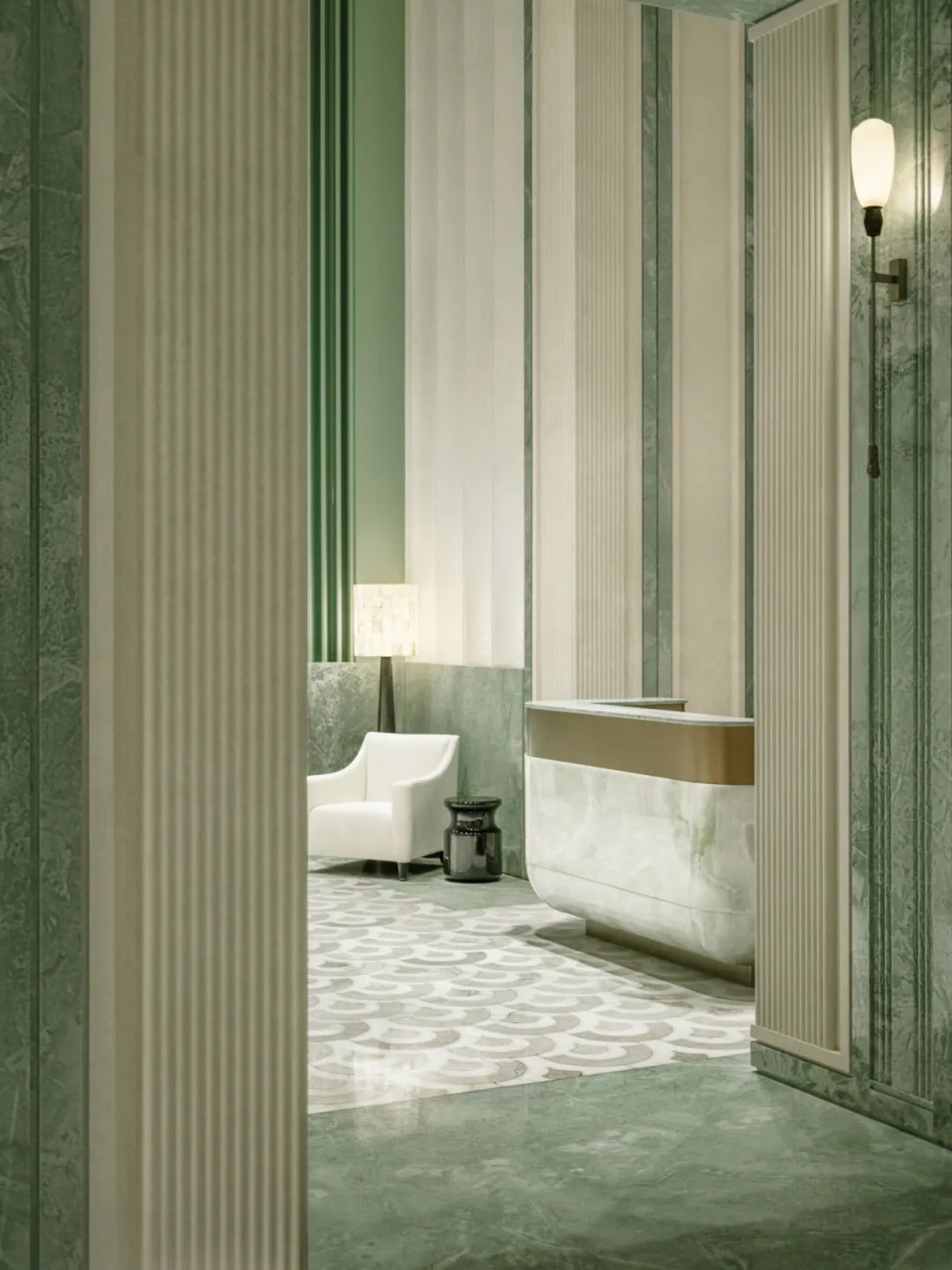 White bathroom with a green accent chair, sink, and bathtub in a dimly lit space