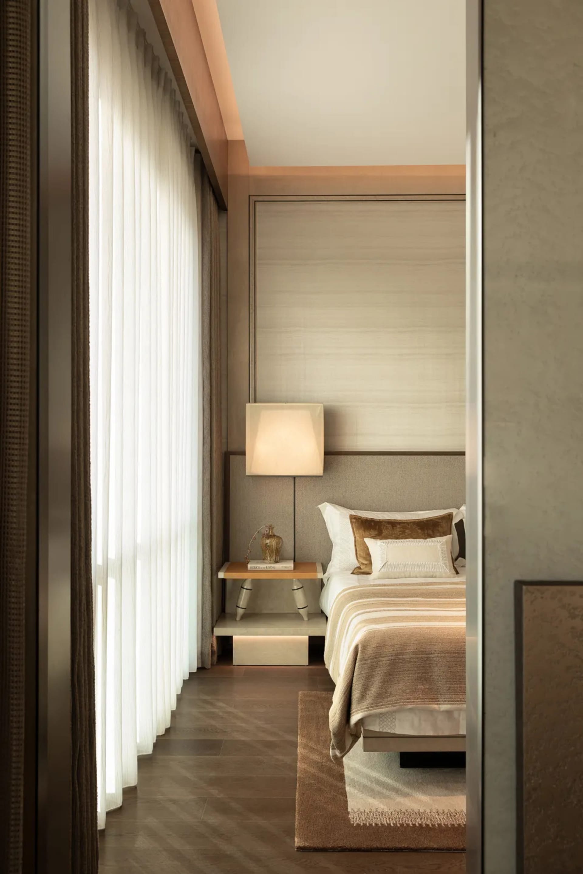 Cozy bedroom with a wooden floor, white curtain, and natural light from an open window