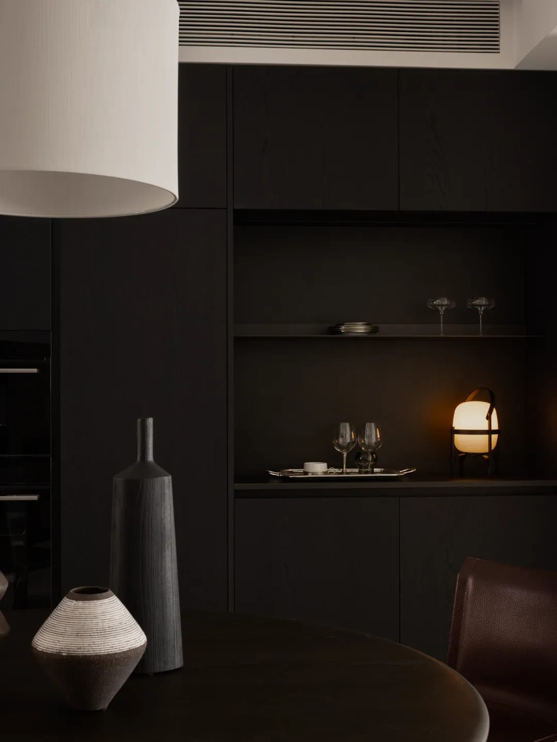 A black and white photograph of a dining area with a wooden table and chairs, wine glasses, and an elegant atmosphere