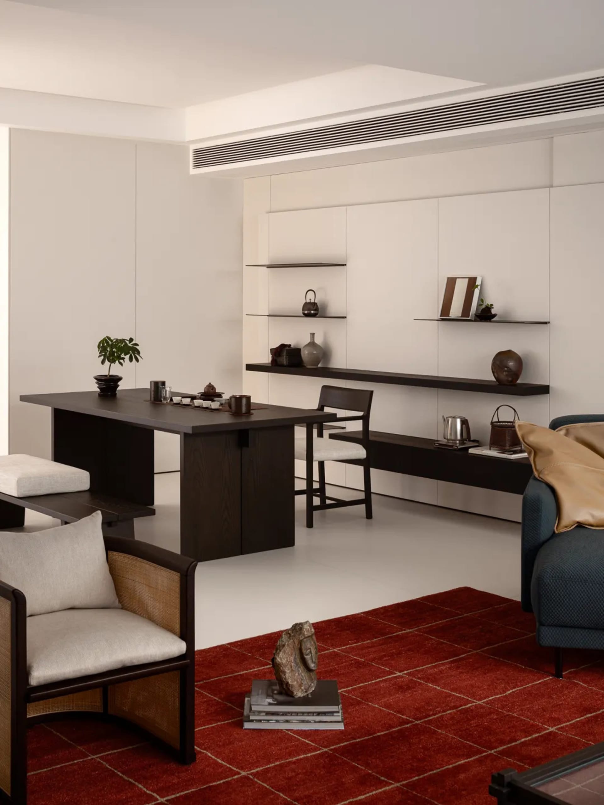A modern living room with a red rug, black furniture, and a white color scheme, well-lit and inviting