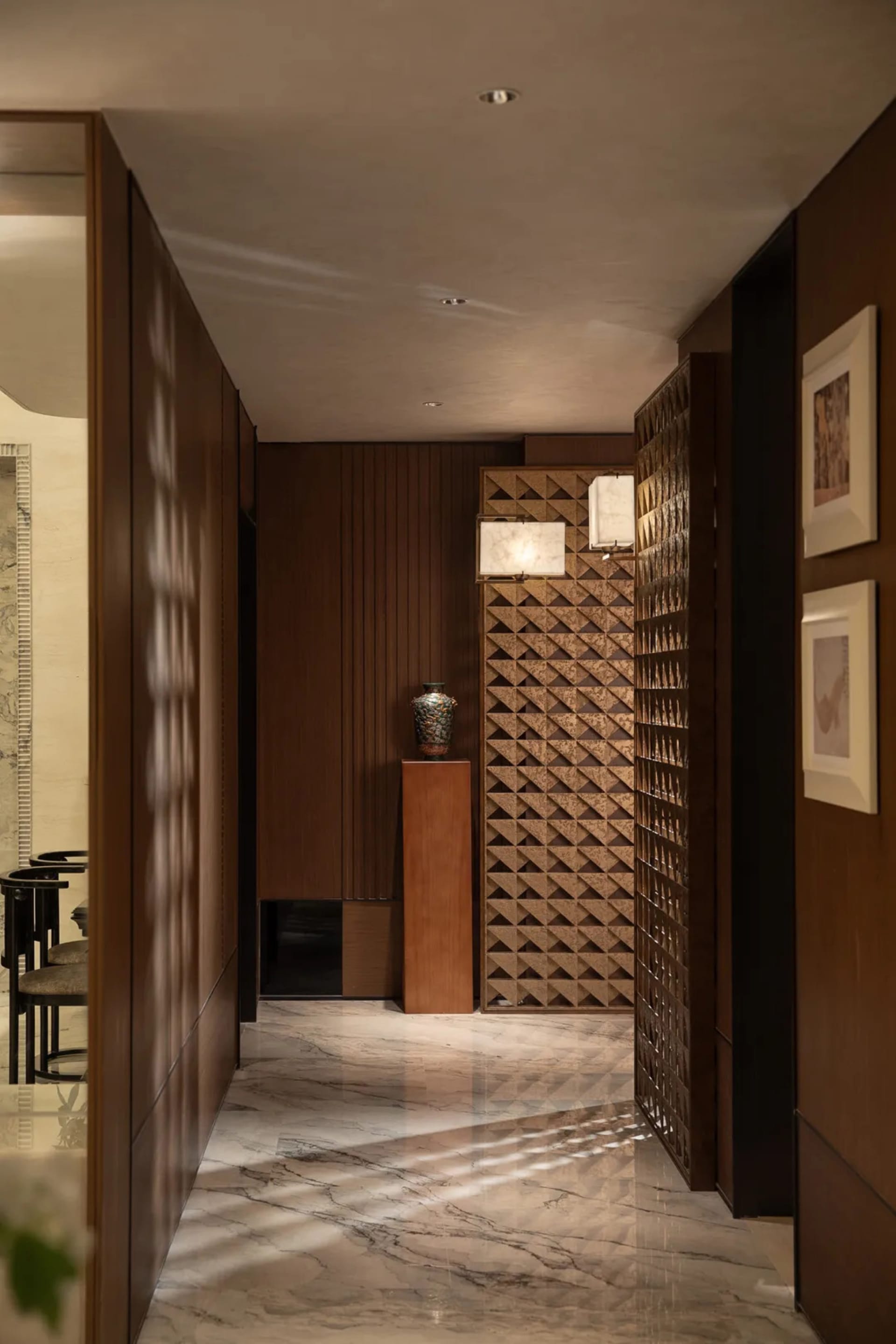 A well-lit modern hallway with wood walls, lined with pictures and chairs, creating a warm and inviting atmosphere