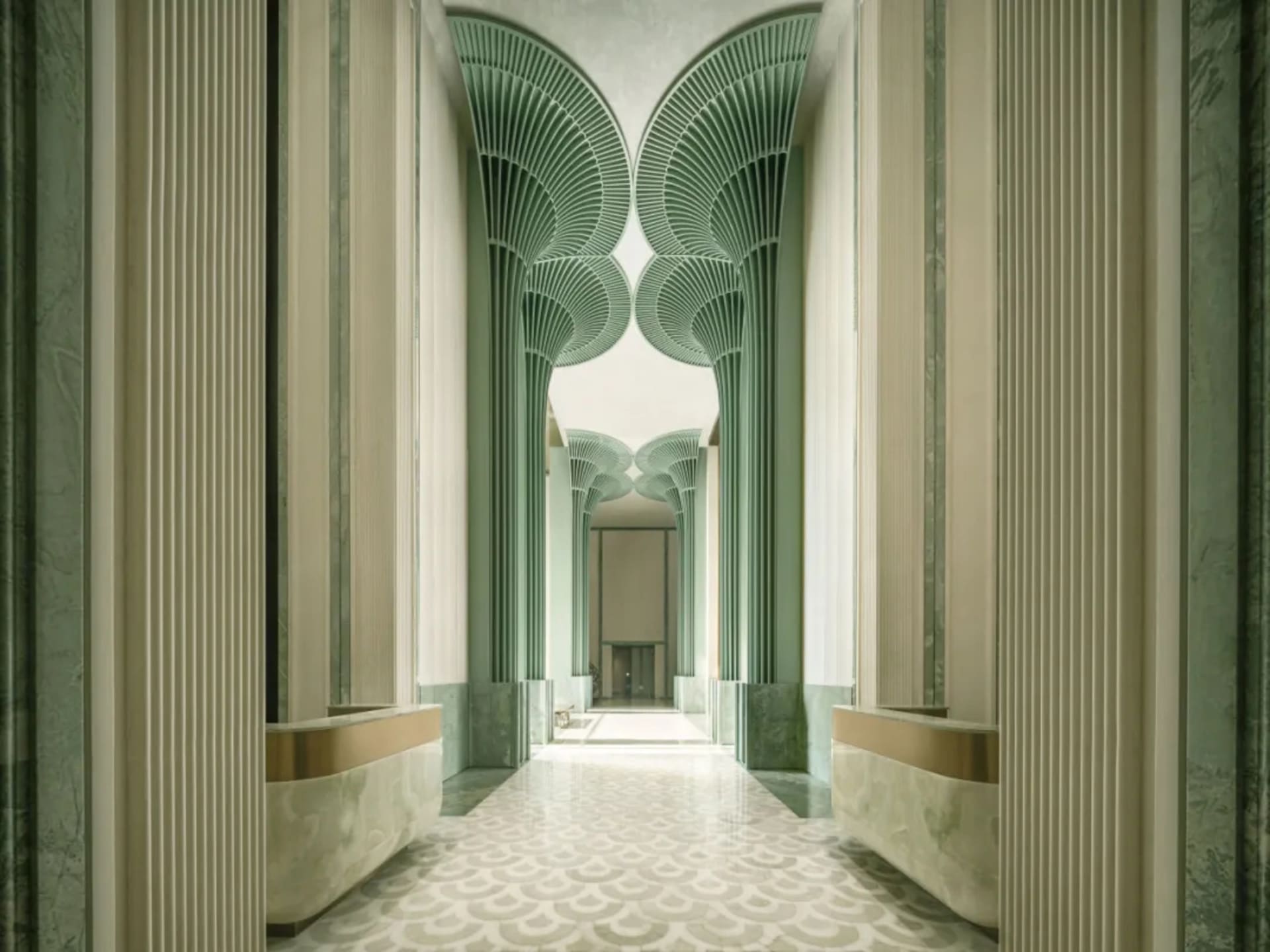 A long, narrow, modern hallway with green walls, arched doorways, and natural light from above, creating a peaceful atmosphere