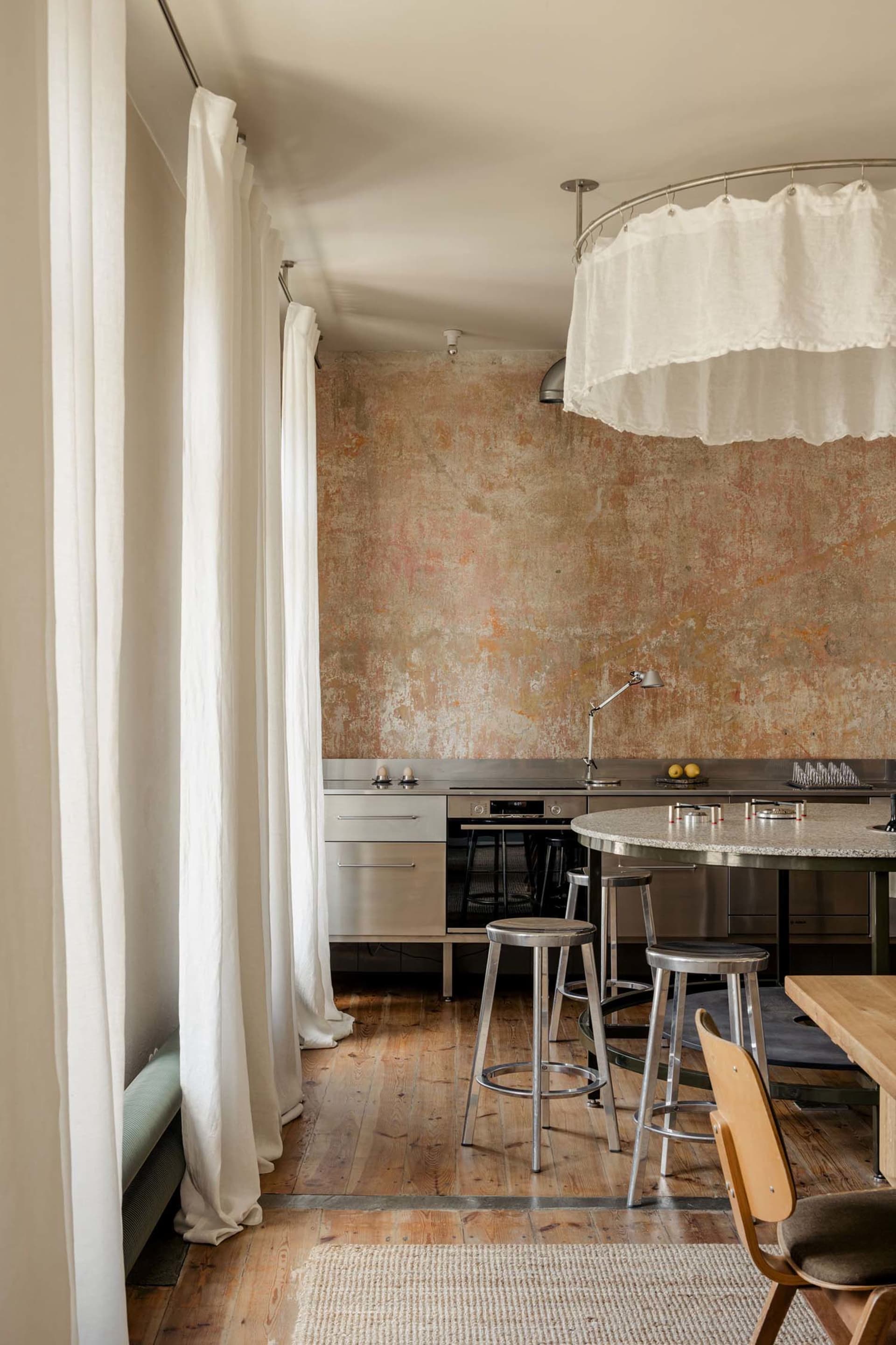 A modern kitchen with a dining table and chairs, surrounded by a wooden floor, sink, and neutral color palette