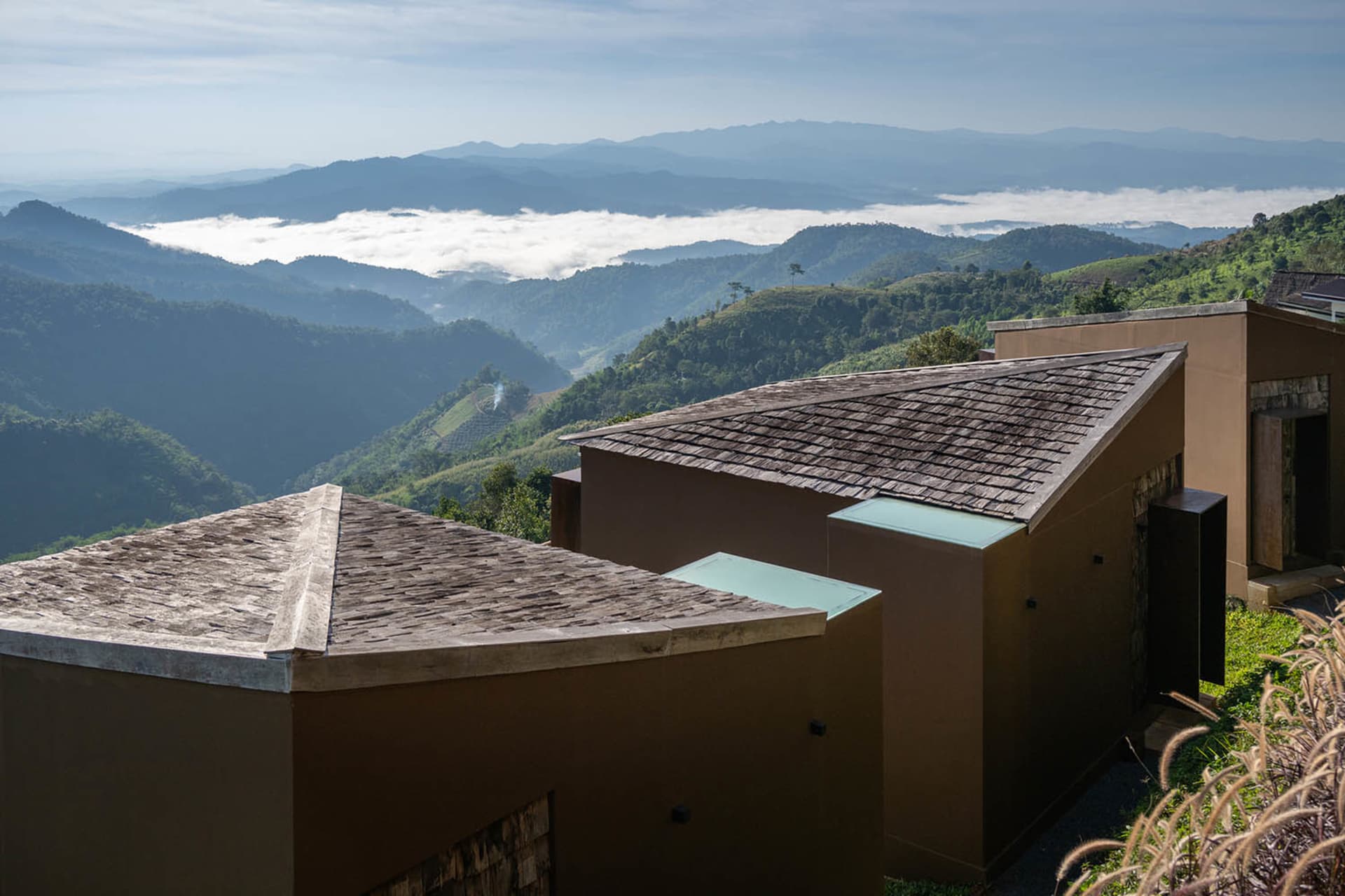 Photograph of a mountainous area with wooden houses built on a hillside, surrounded by mountains and natural scenery