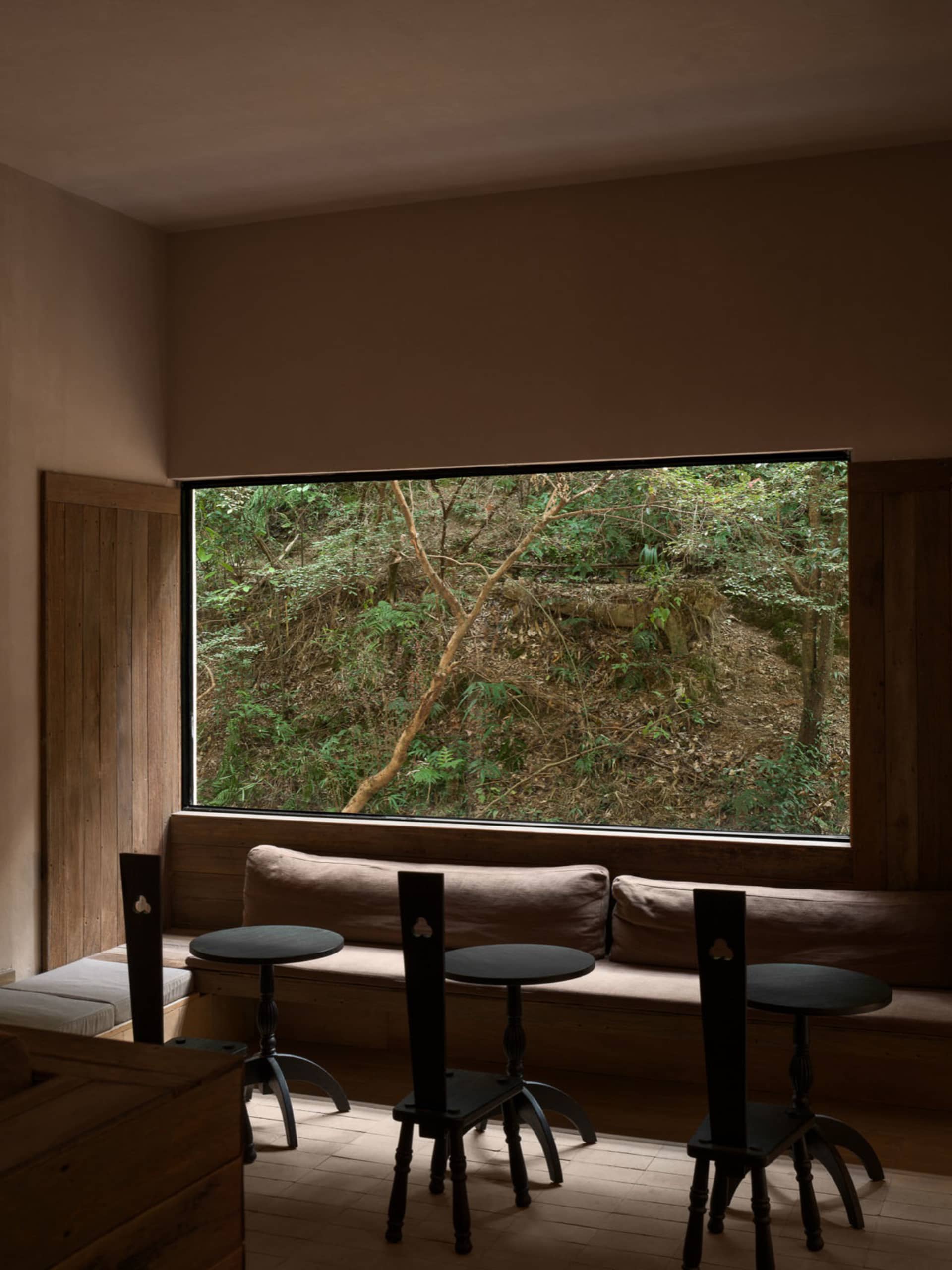 Cozy modern living space with a brown couch, a wooden chair, and natural light from a window