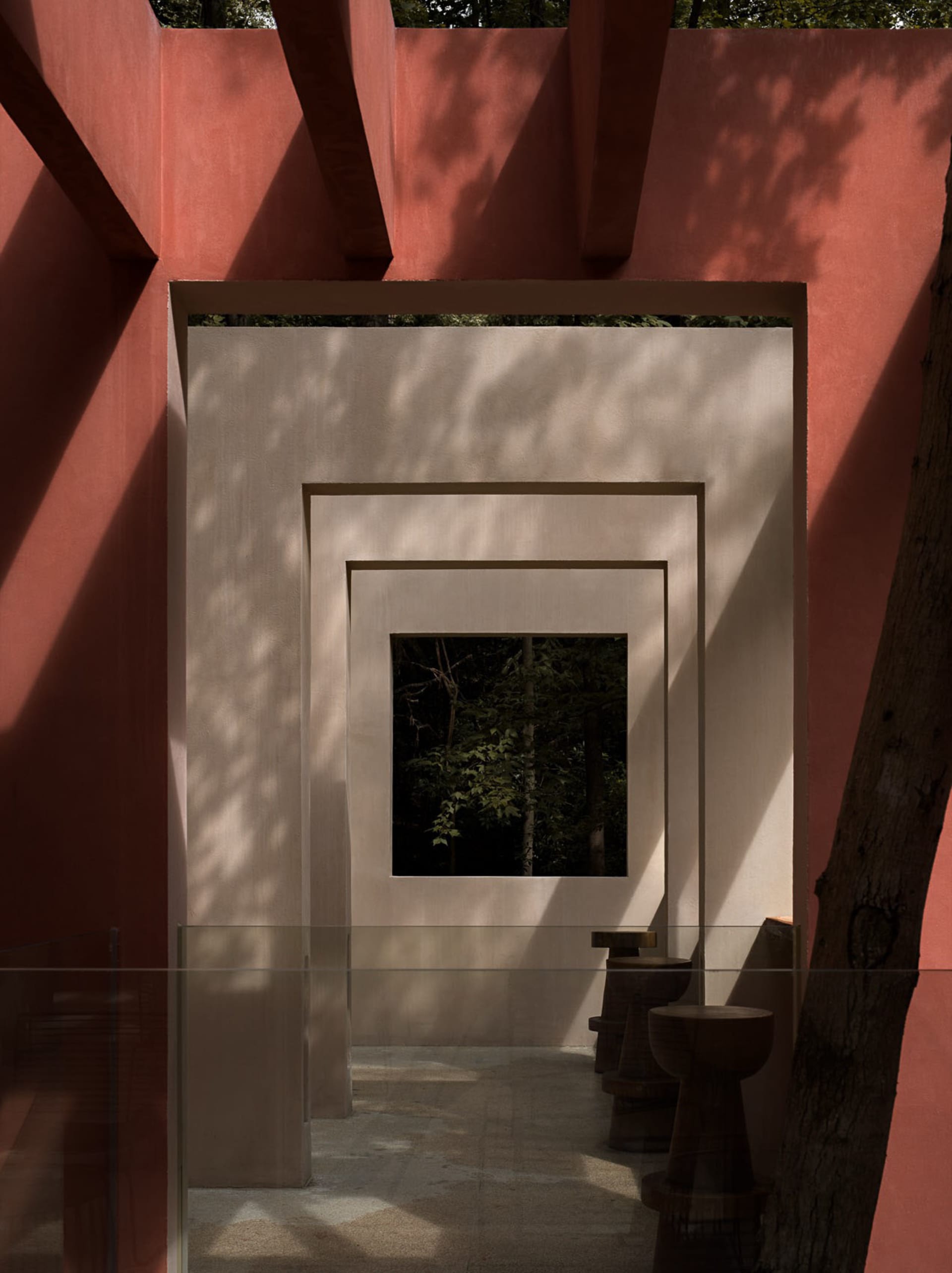 Dimly lit bathroom with two toilets, a red wall, and concrete walls
