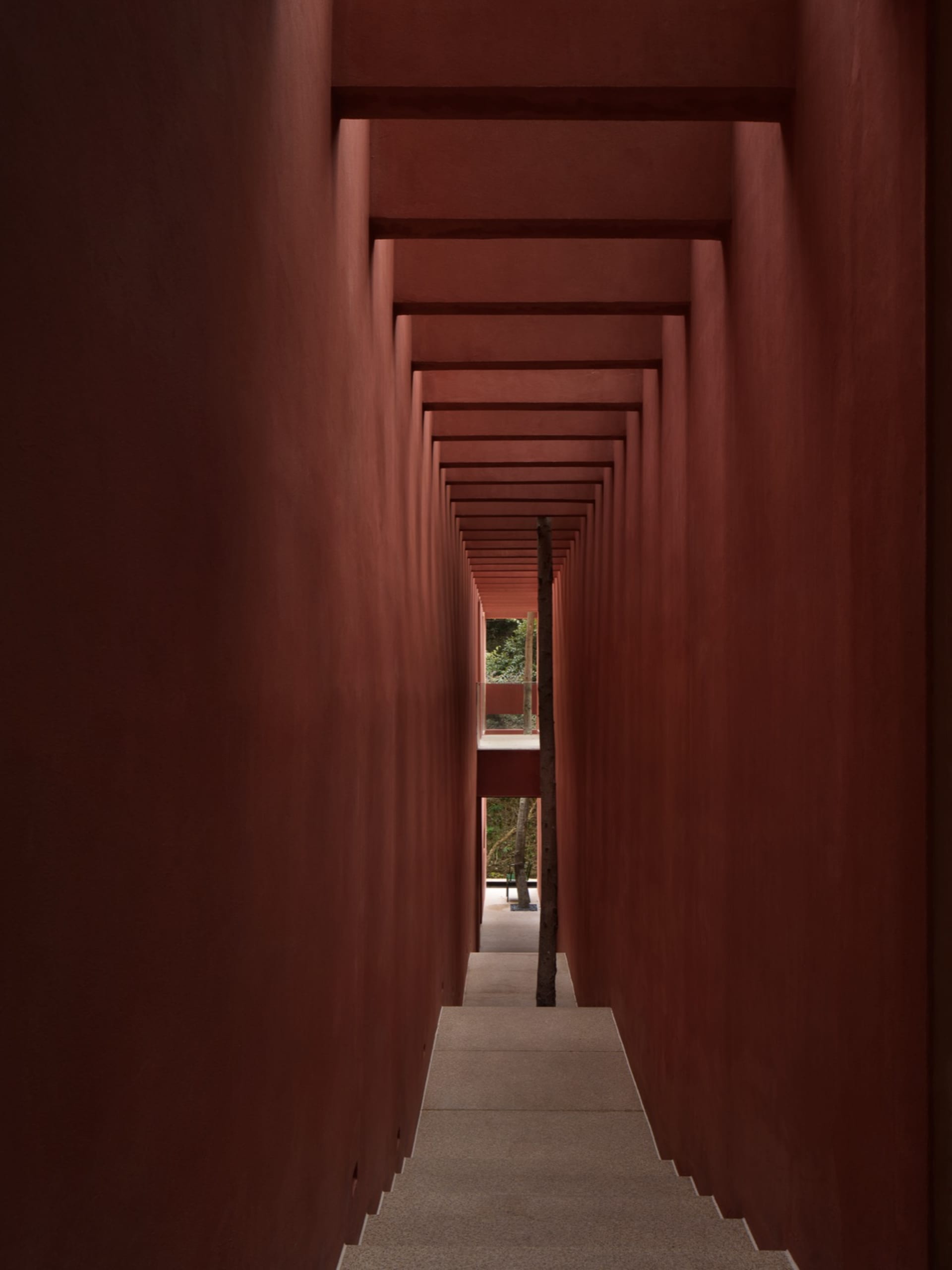 Narrow hallway with a red brick wall, dim lighting, and a moody atmosphere