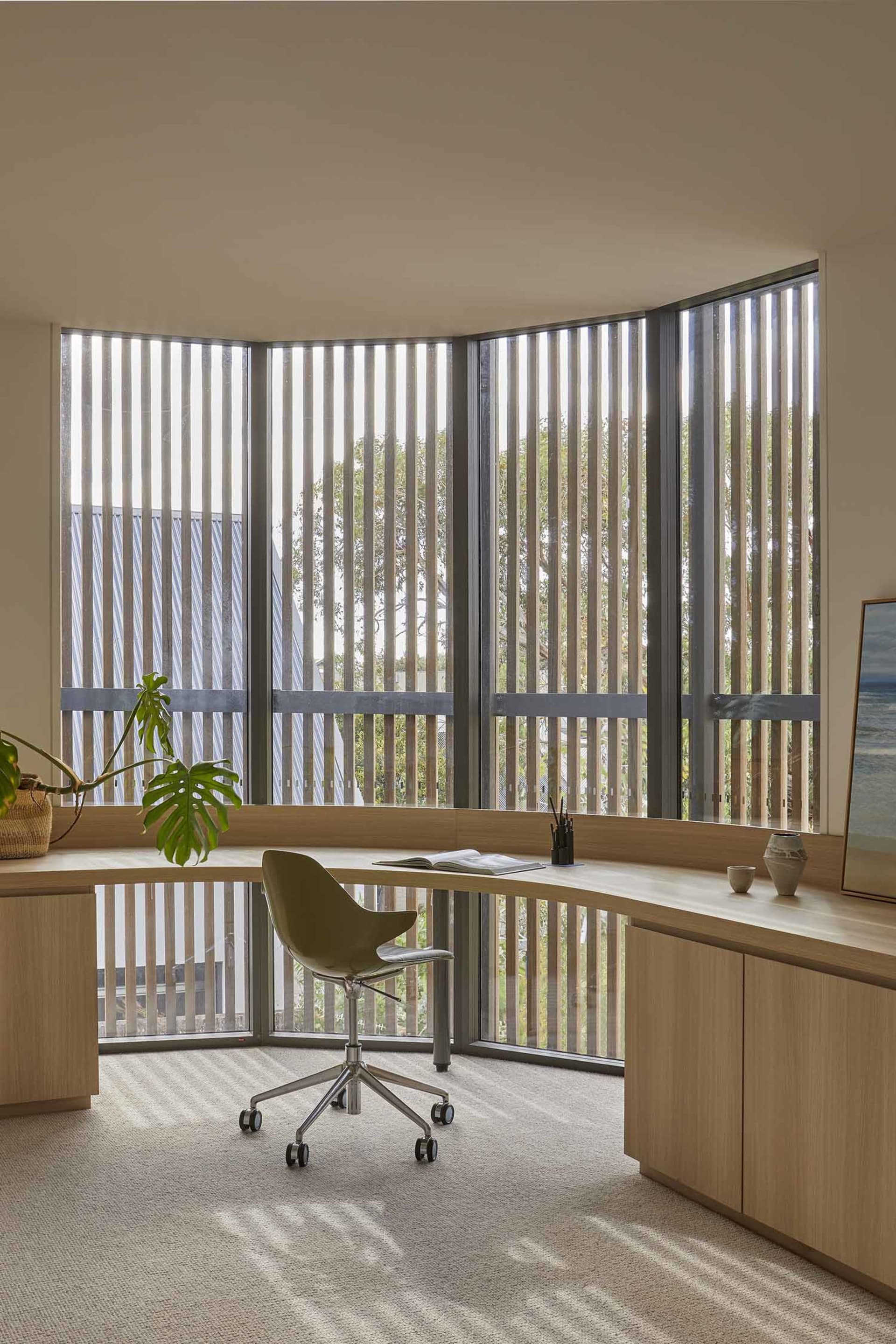 A well-organized home office with a wooden desk, a green chair, and natural light from a window