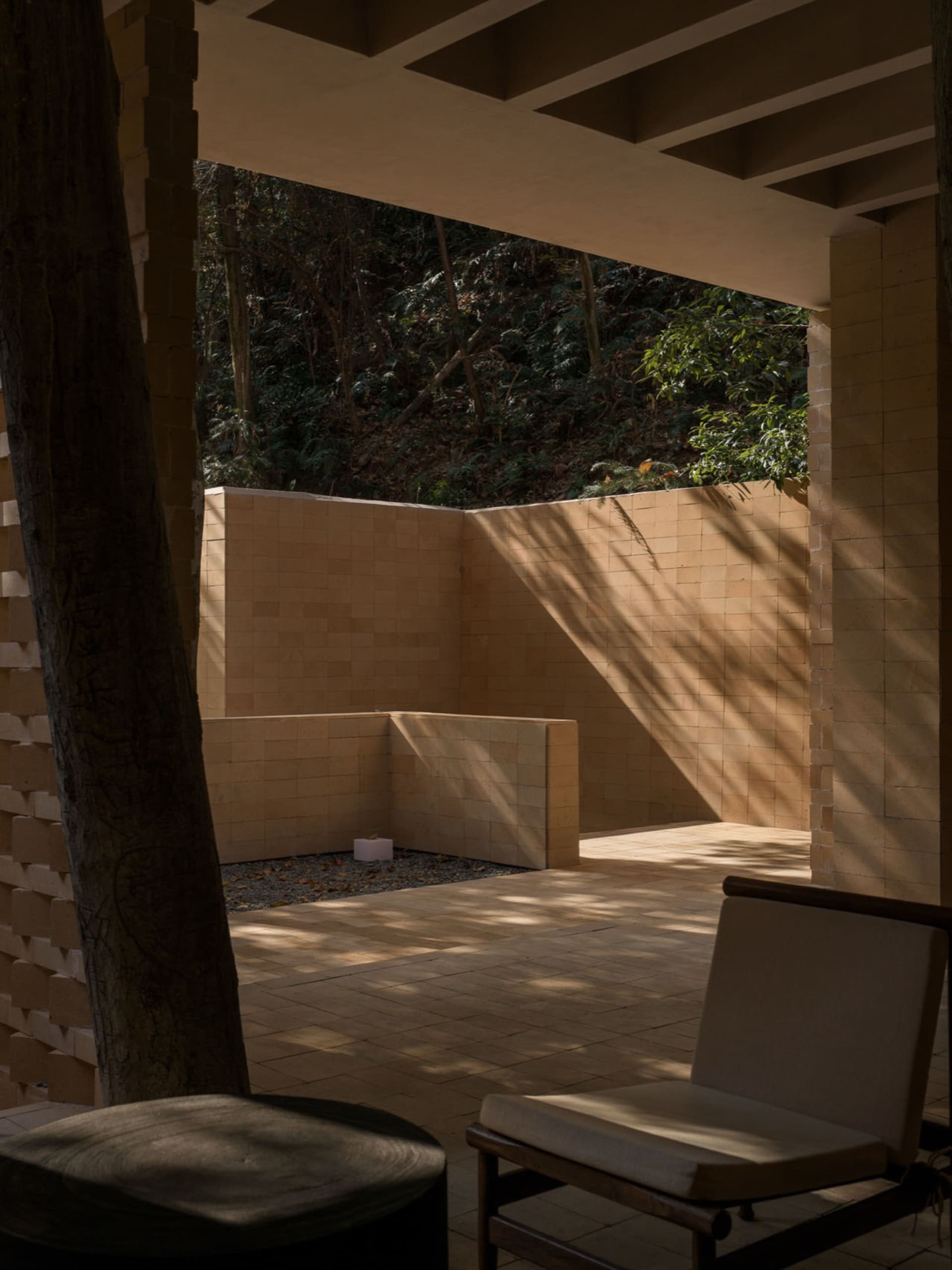 A stone-walled outdoor living space with a bench and chair, inviting relaxation and socializing