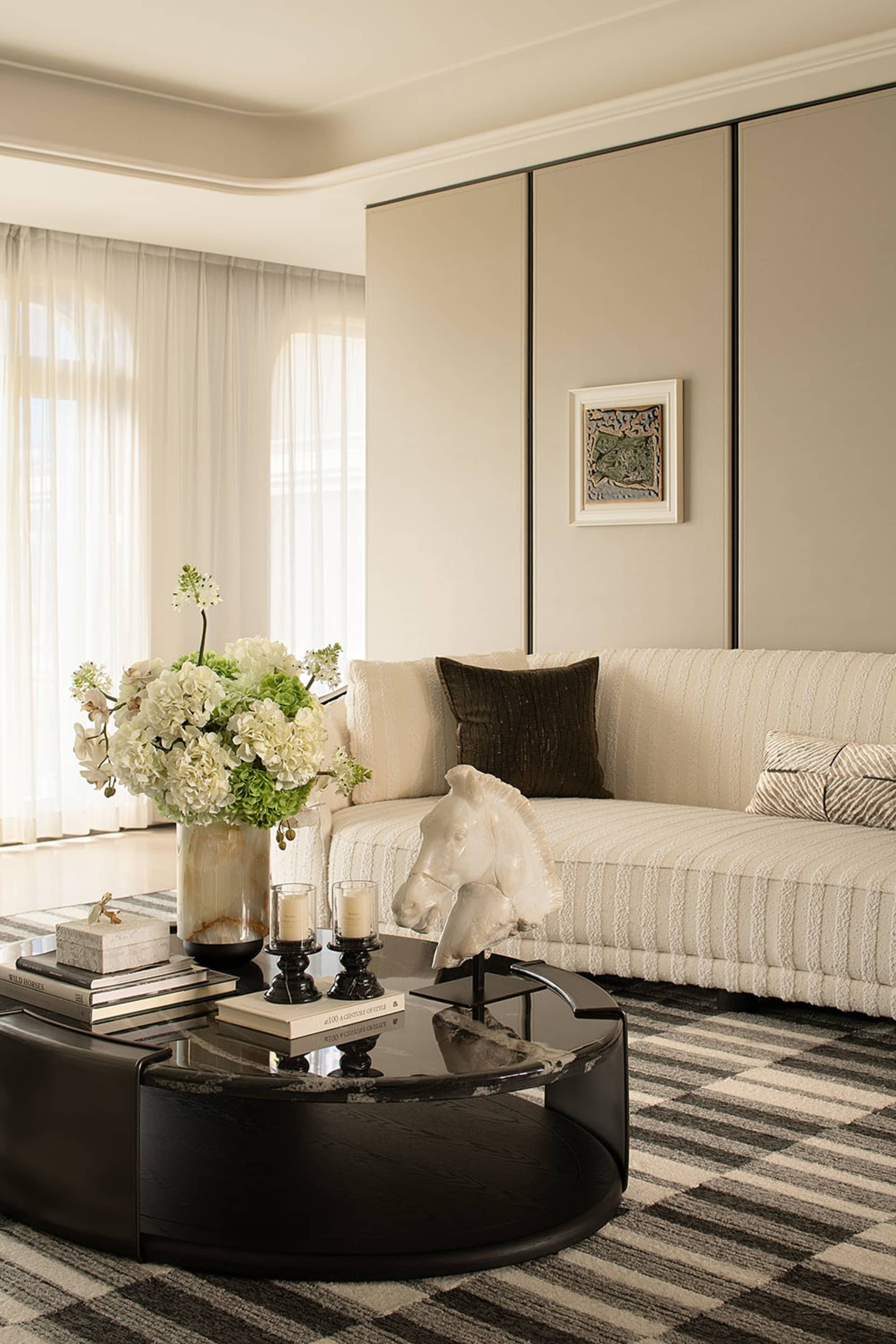 A well-lit living room with a couch, coffee table, and a vase with flowers on it